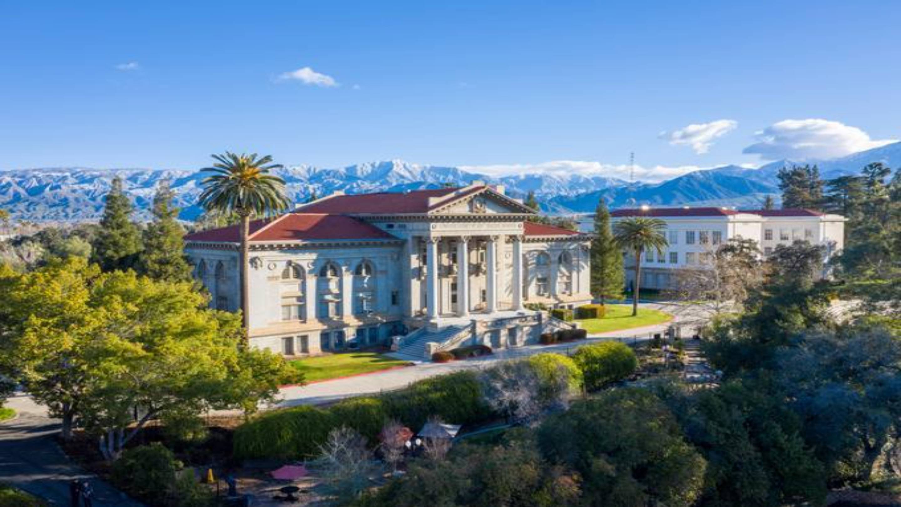 a large building with trees and mountains in the background