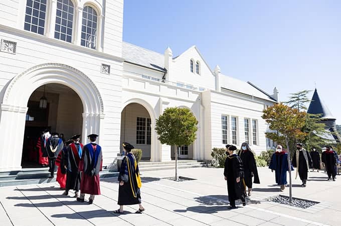 a group of people wearing graduation gowns outside a building