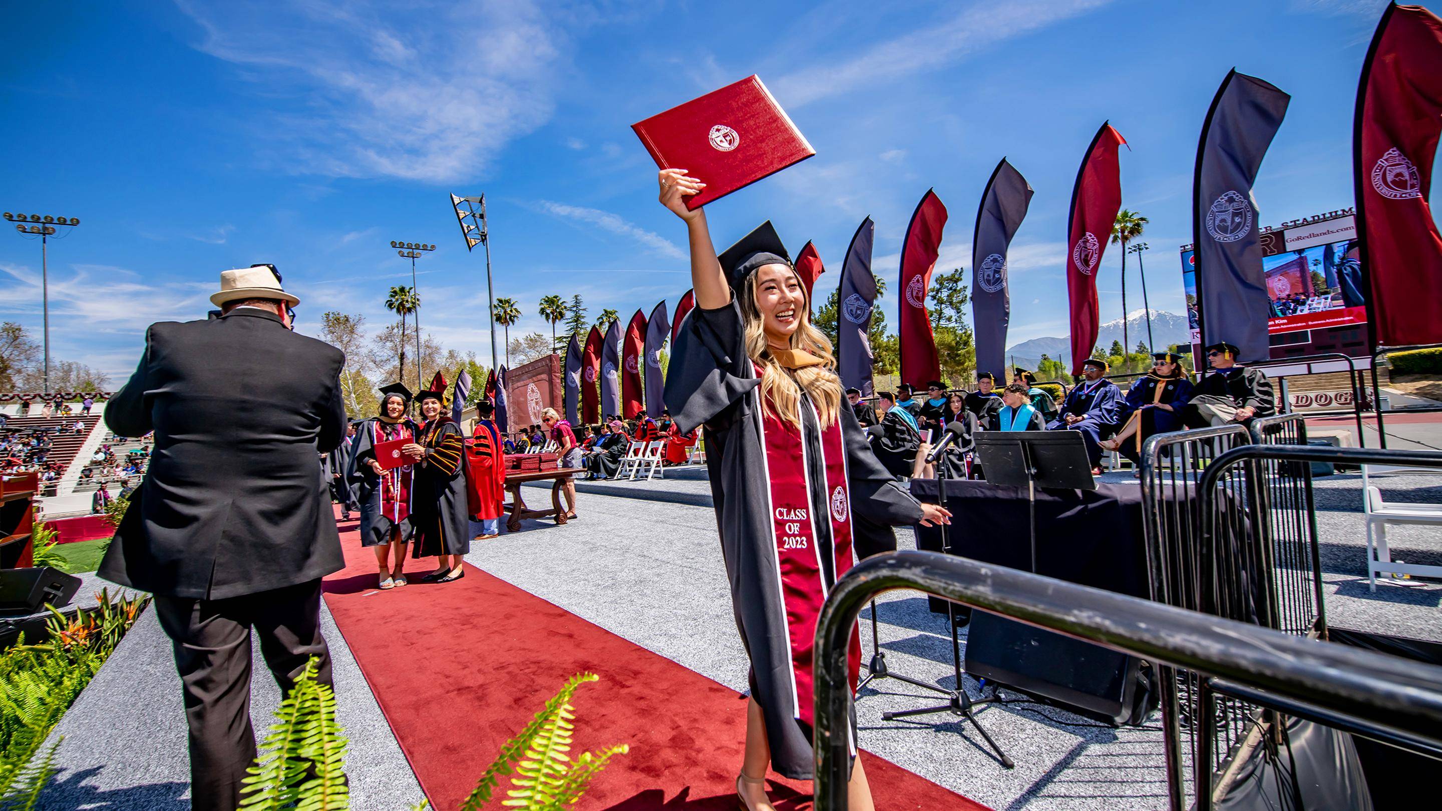 a person in a graduation gown and cap waving in the air