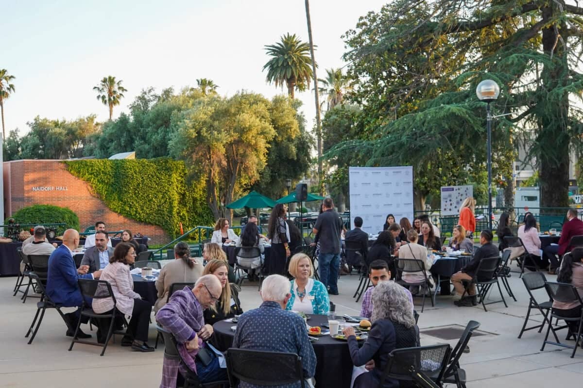a group of people sitting at tables outside