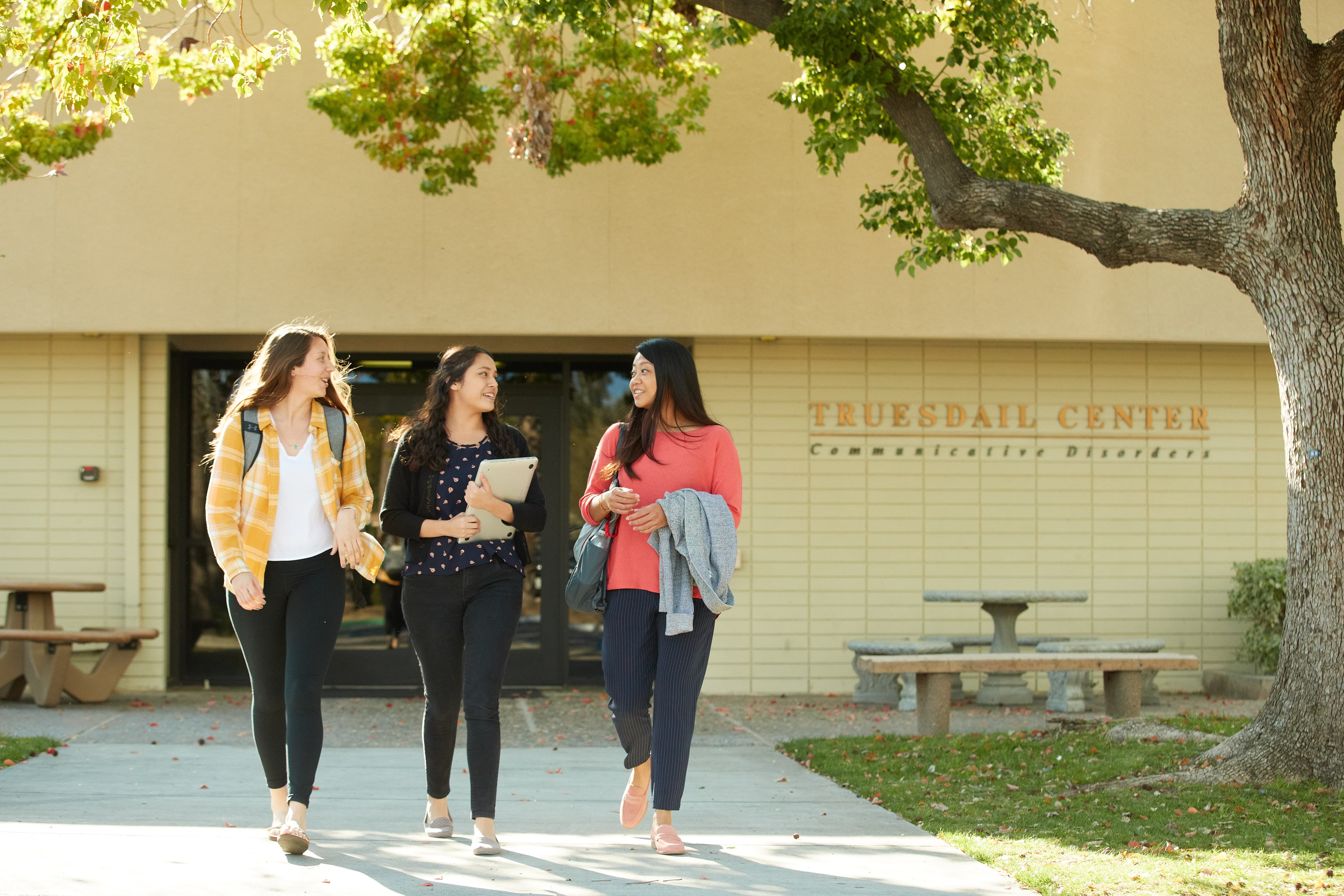 a group of women walking on a sidewalk