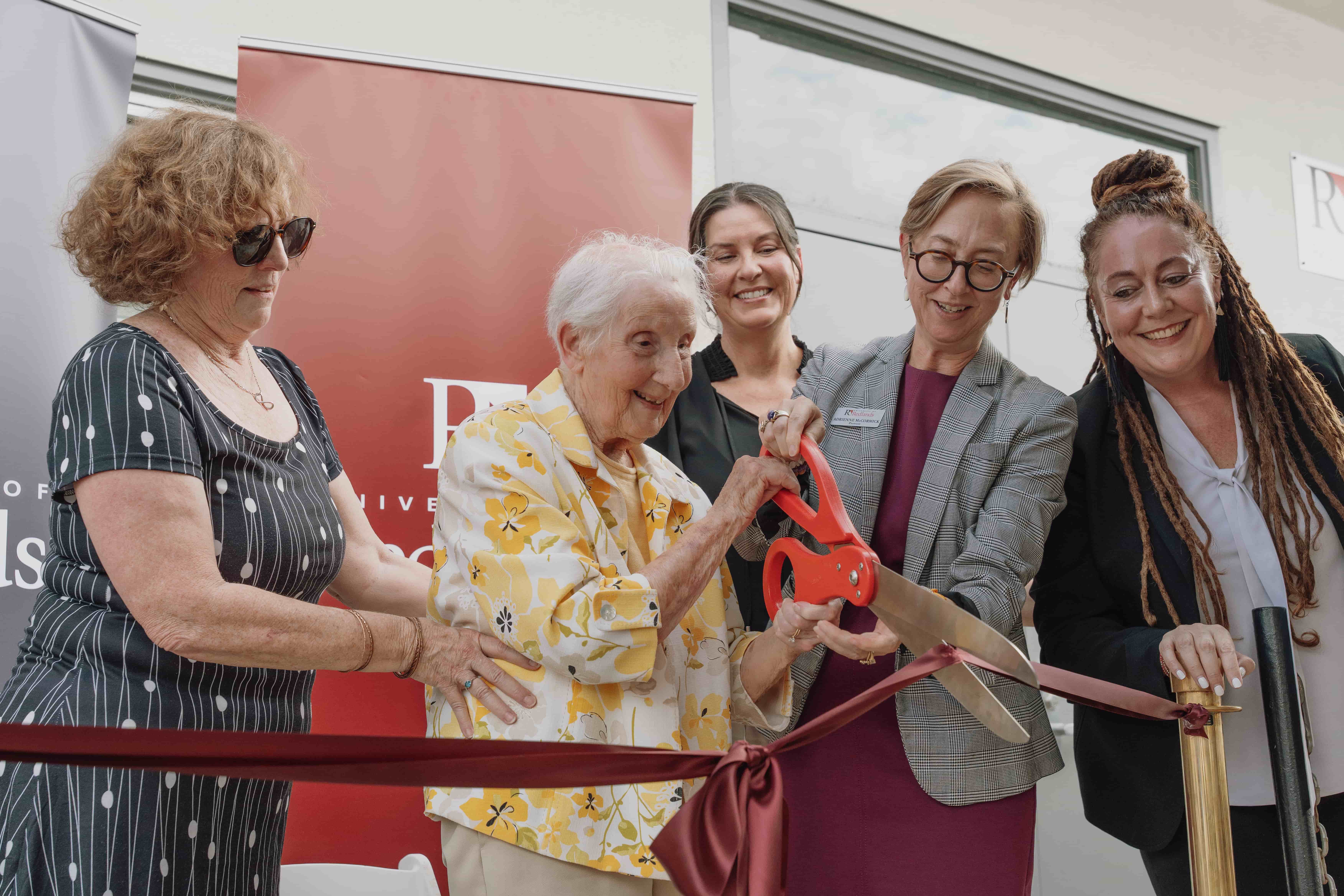 a group of women cutting a ribbon