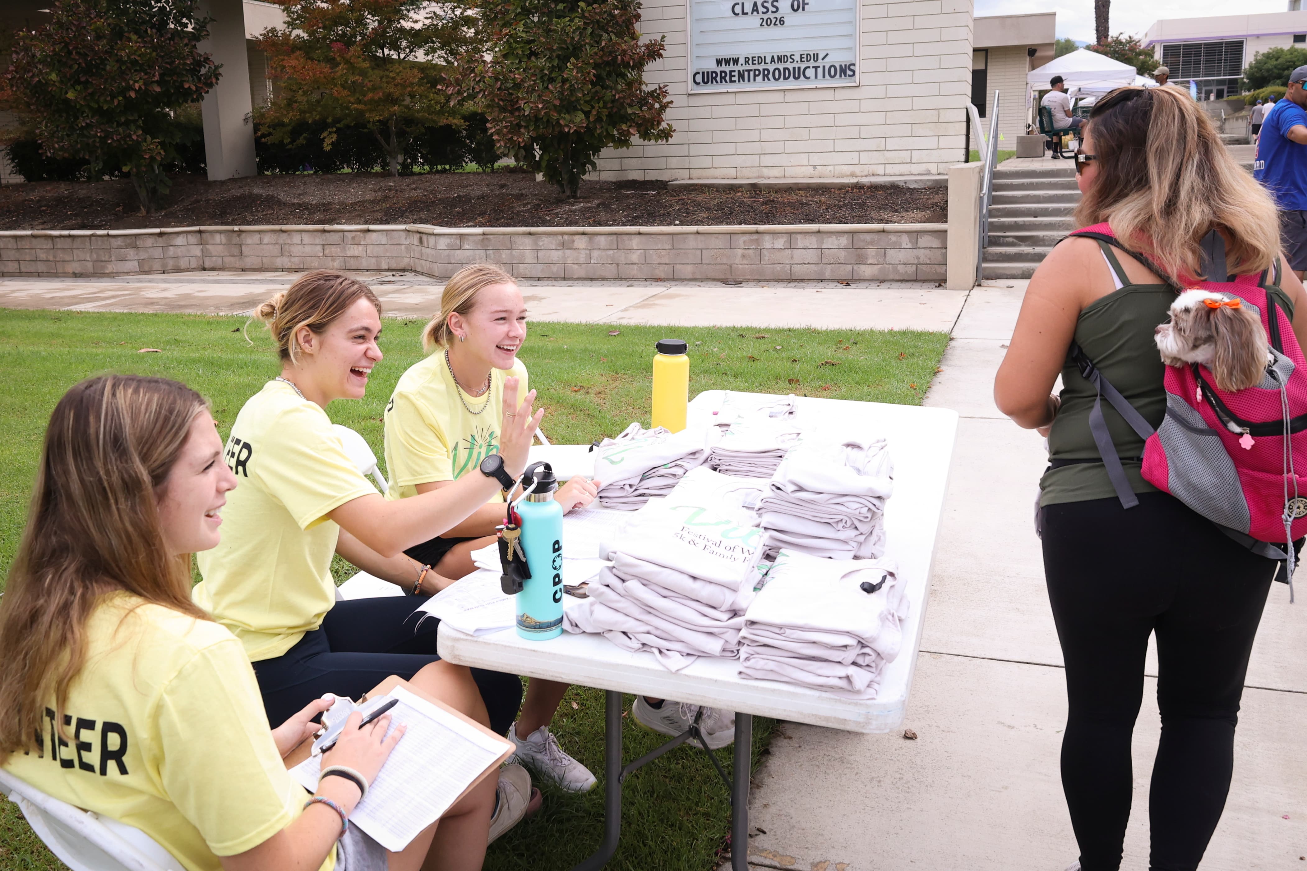 a group of women sitting at a table with folded t-shirts