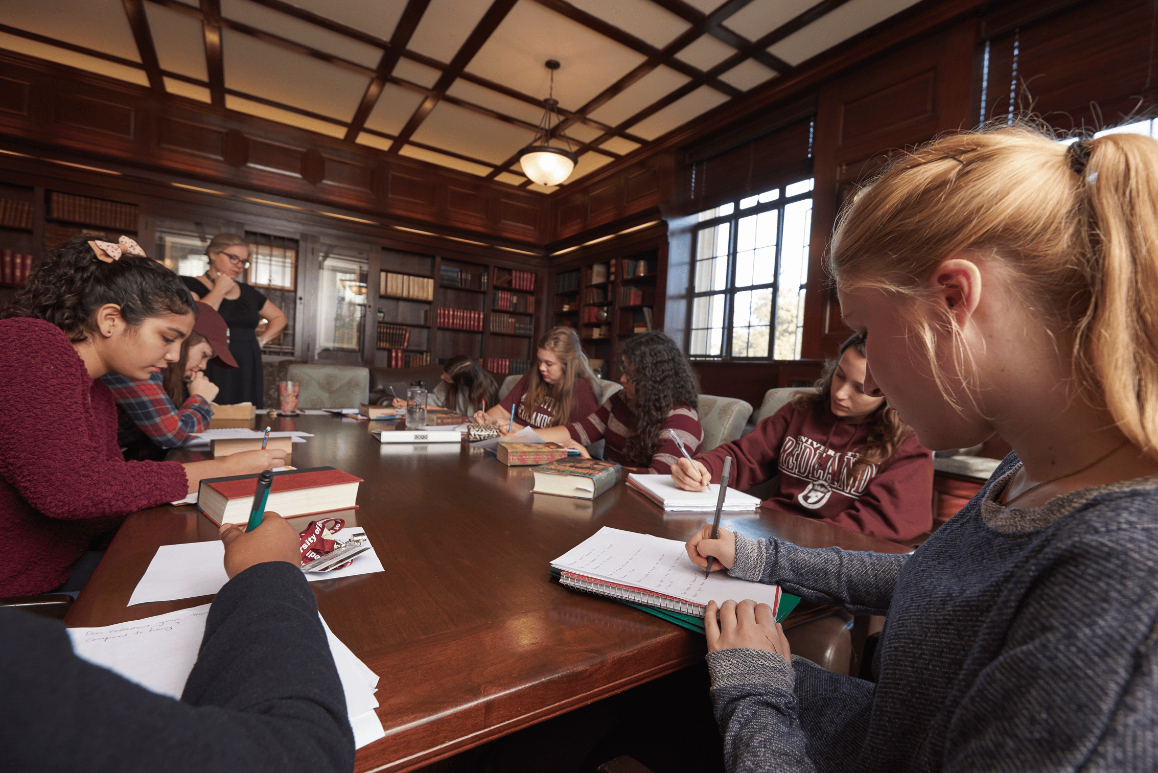 a group of people sitting at a table writing on books