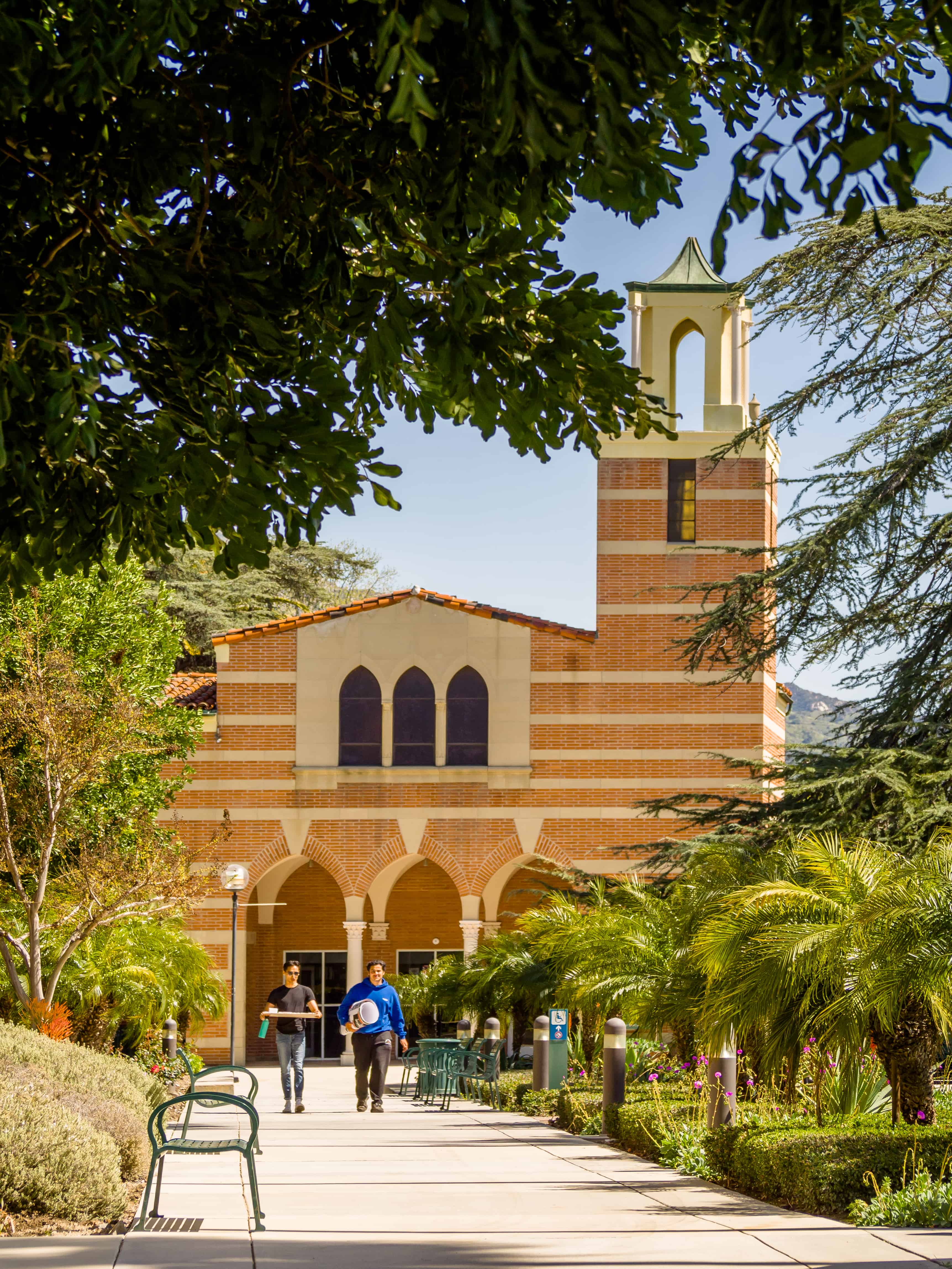 a building with a bell tower and people walking in front of it