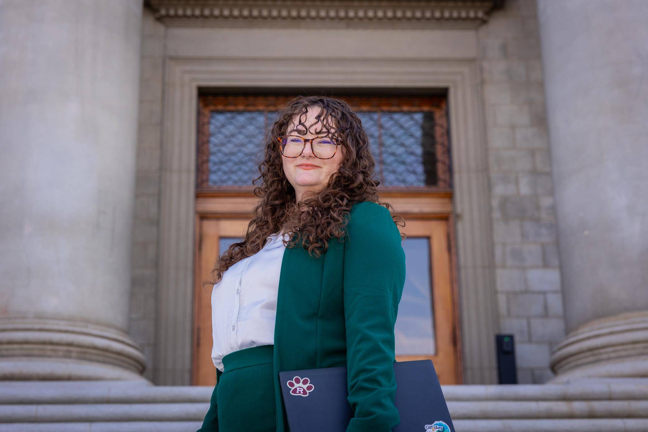 a person in green suit holding a laptop