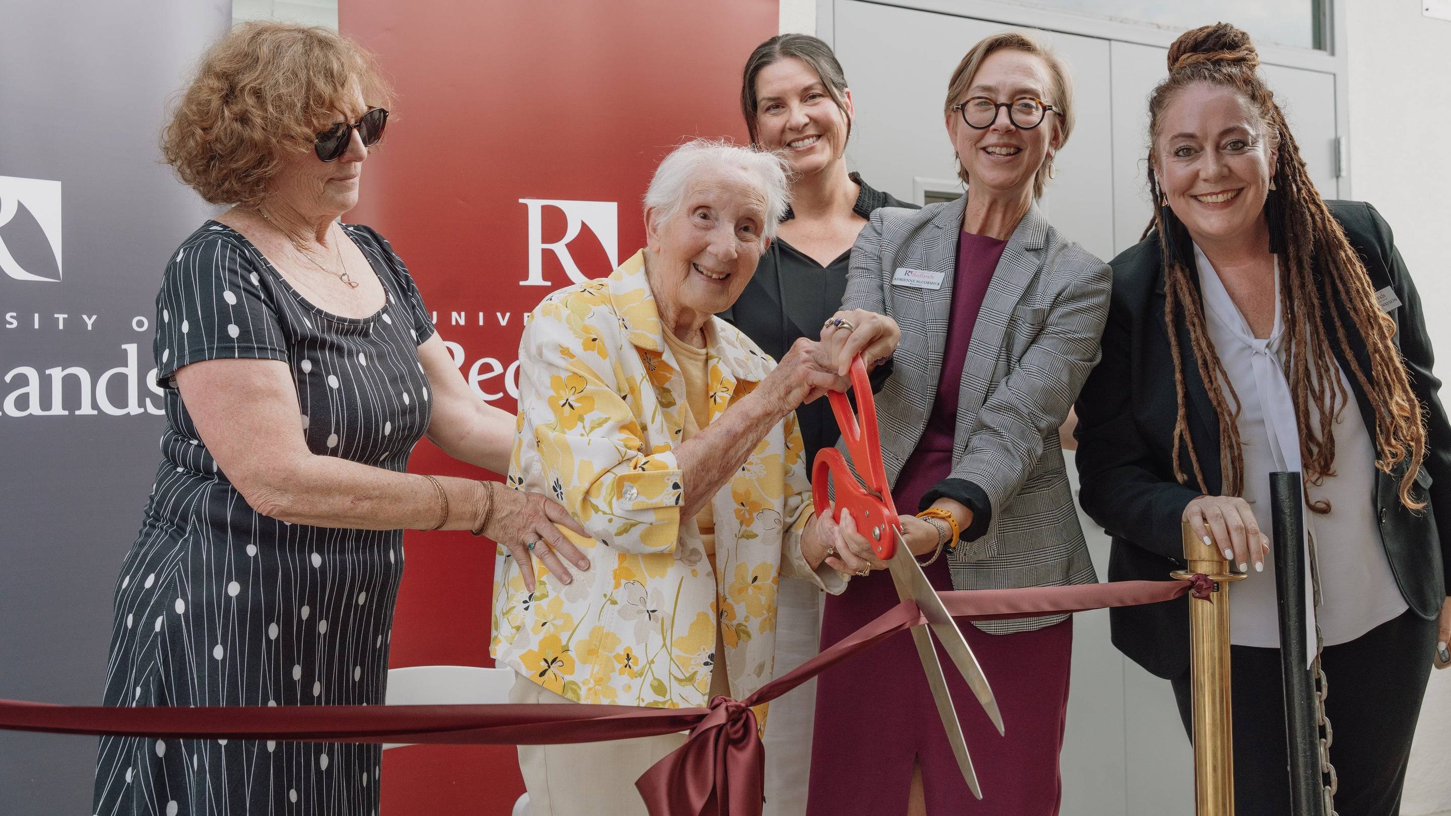a group of women cutting a ribbon