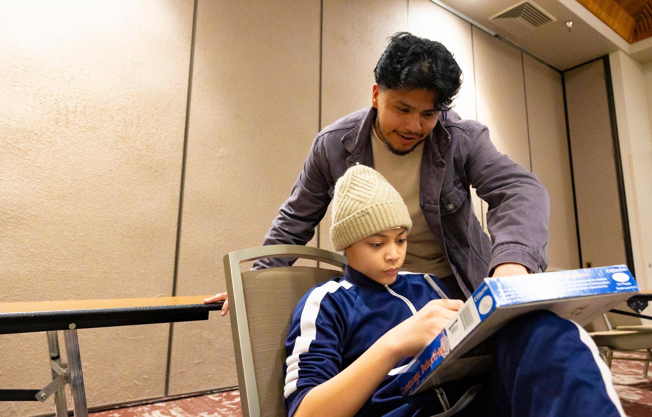 a person and child sitting in a chair looking at a book