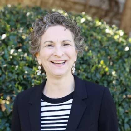 a person smiling in front of a bush