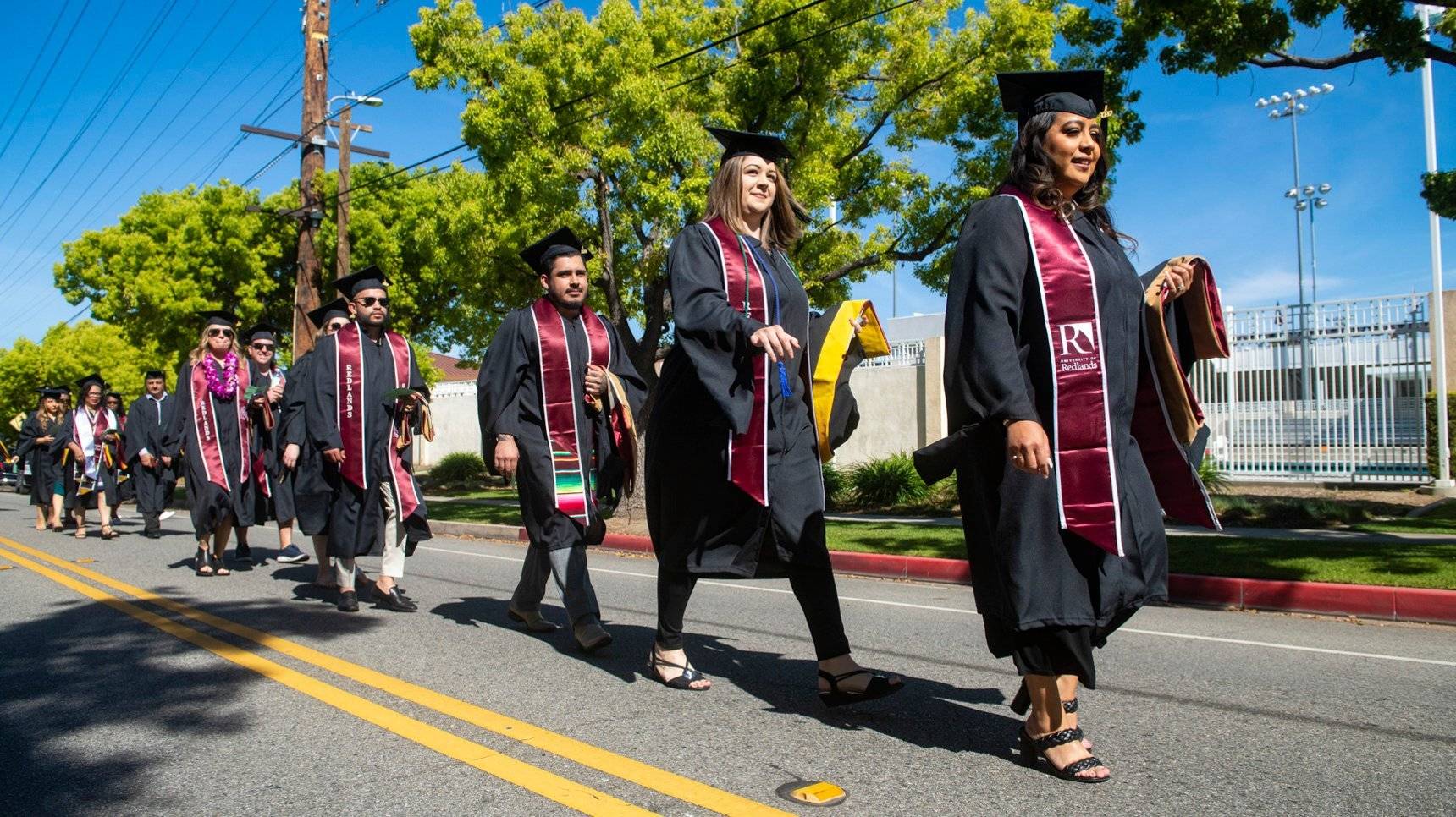 a group of people in graduation gowns walking down the street