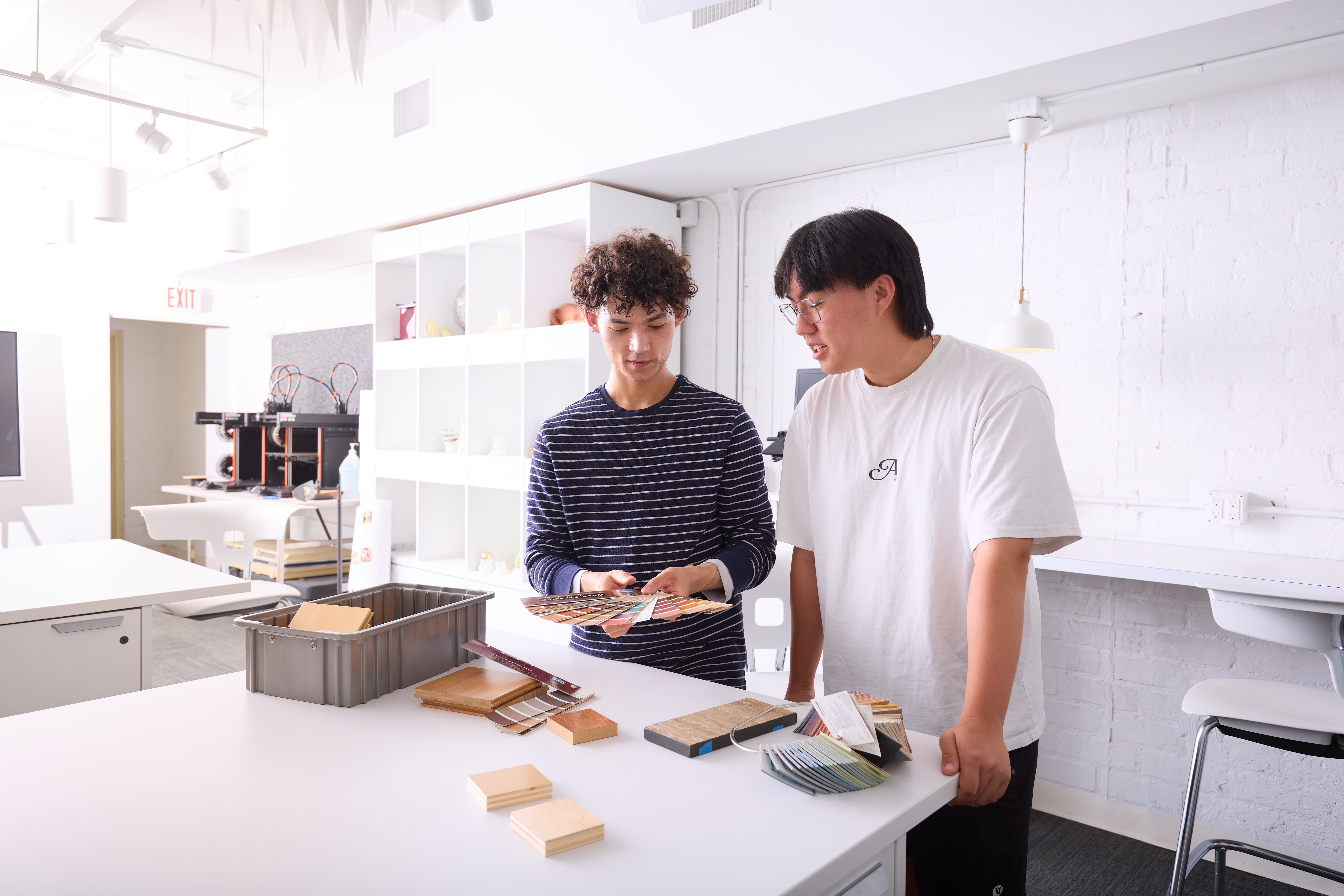 a couple of men standing next to a table with a color swatch