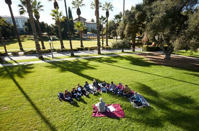a group of people sitting in a circle on the grass