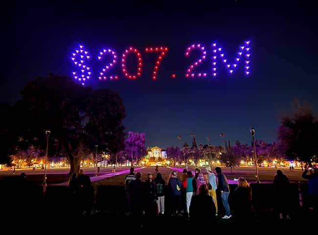 a group of people standing in a park with lights in the sky