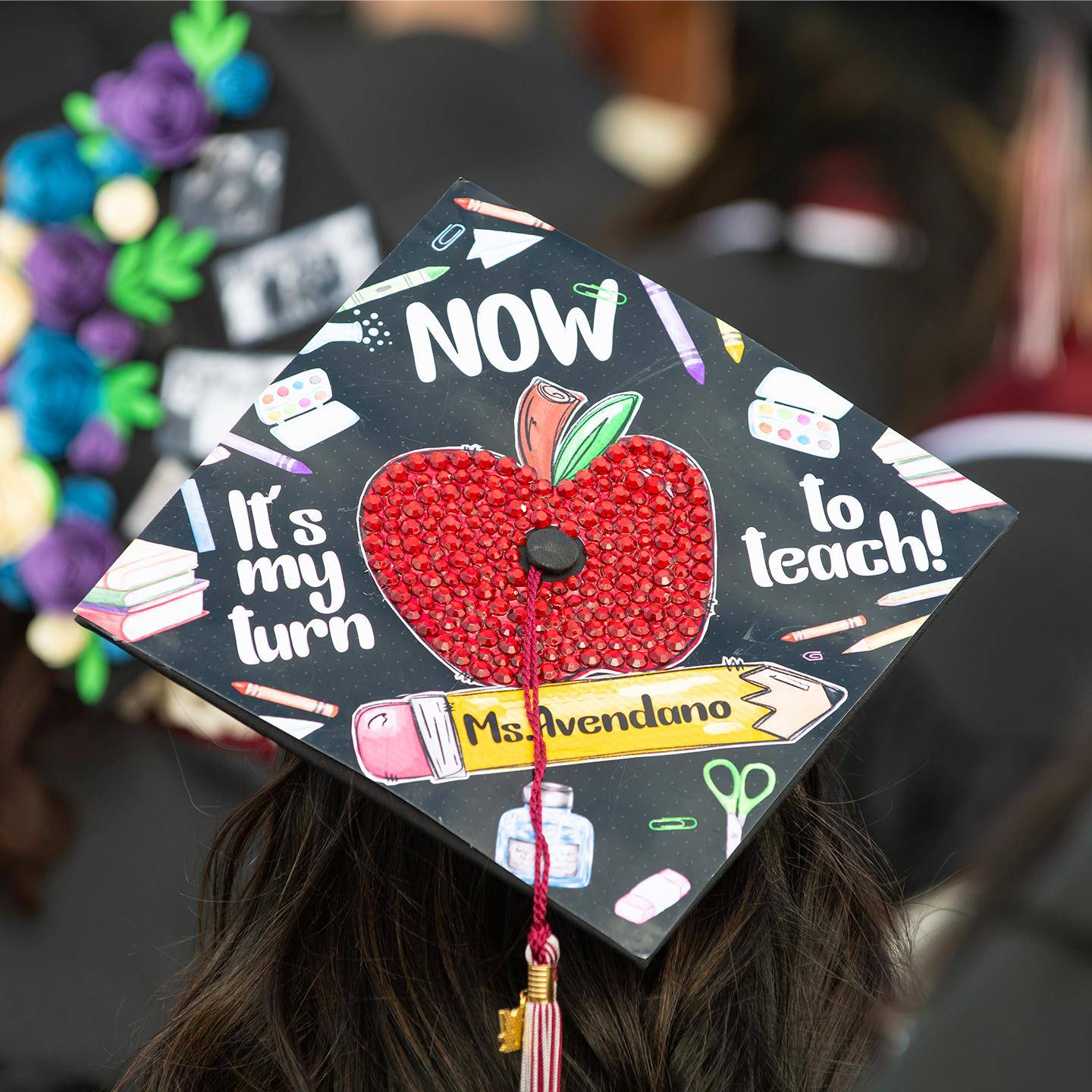 a graduation cap with a red apple on the back