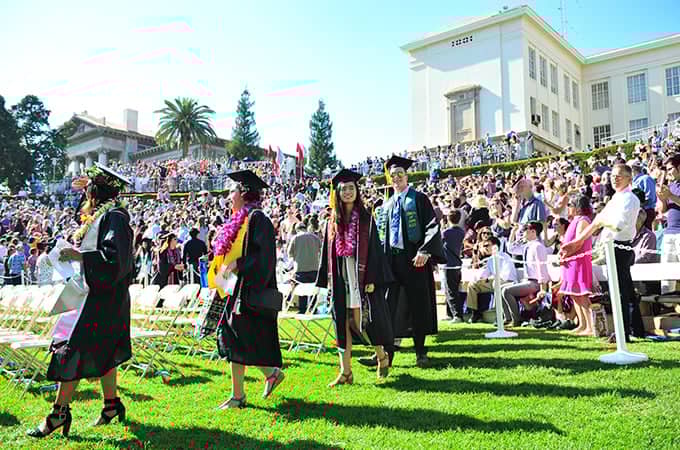 a group of people in graduation gowns and caps walking in a field