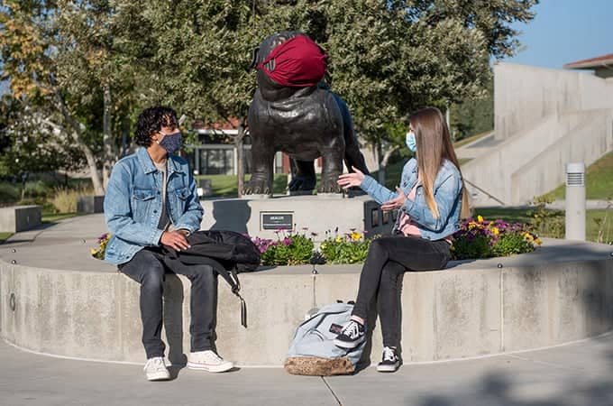 a person and person wearing face masks sitting on a concrete bench