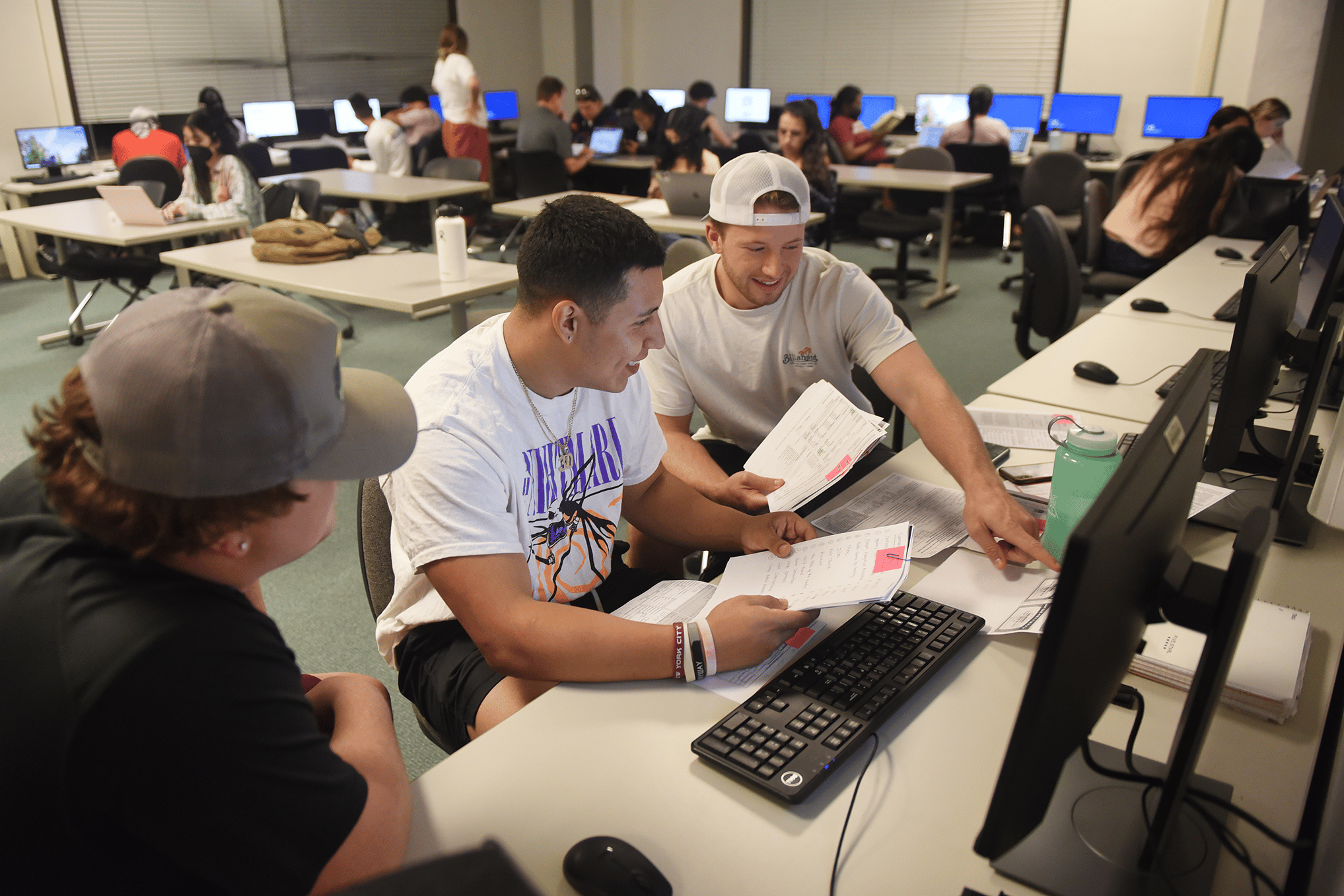 a group of people sitting at a desk with computers
