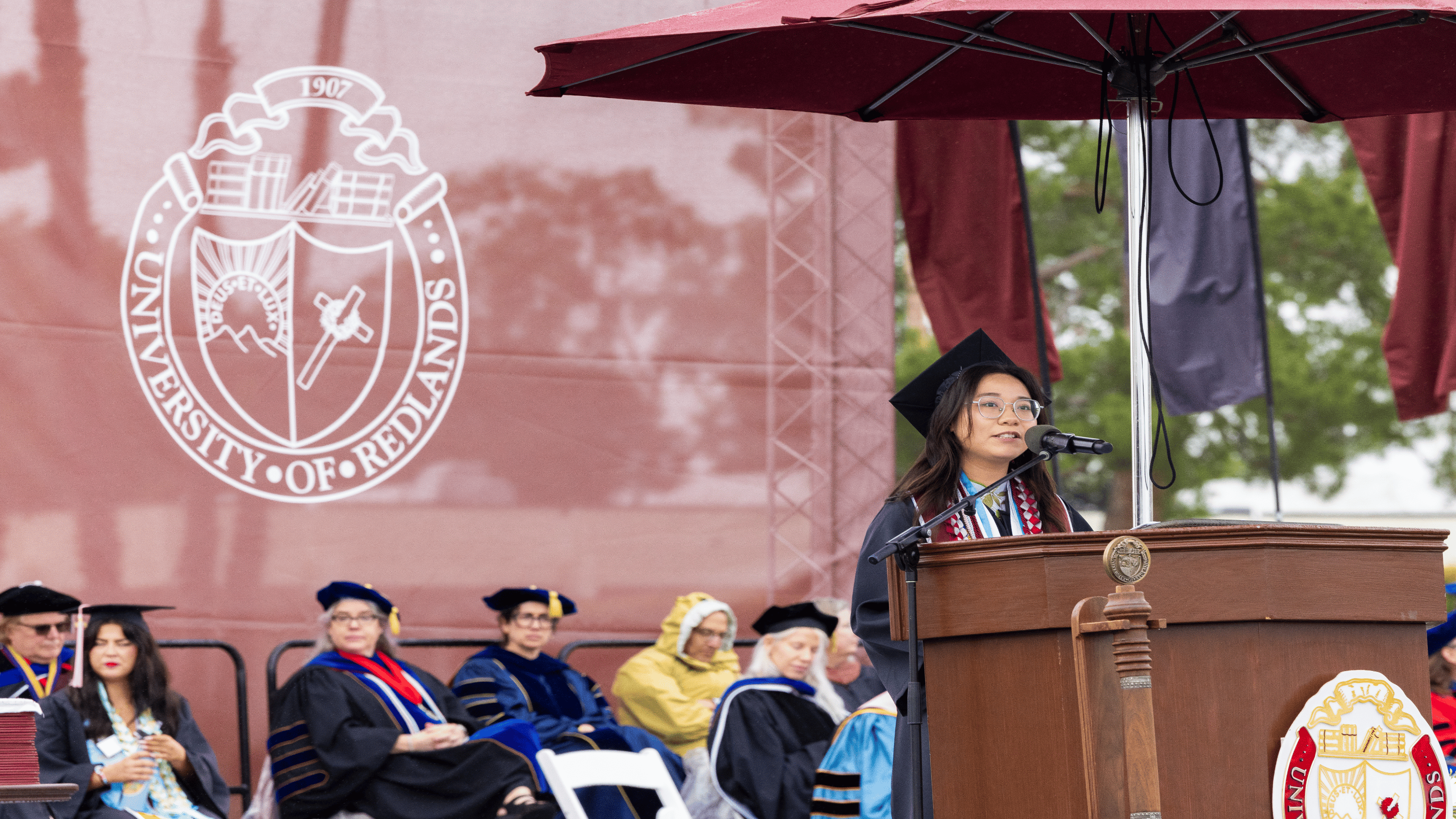 a person in a graduation cap and gown speaking into a microphone
