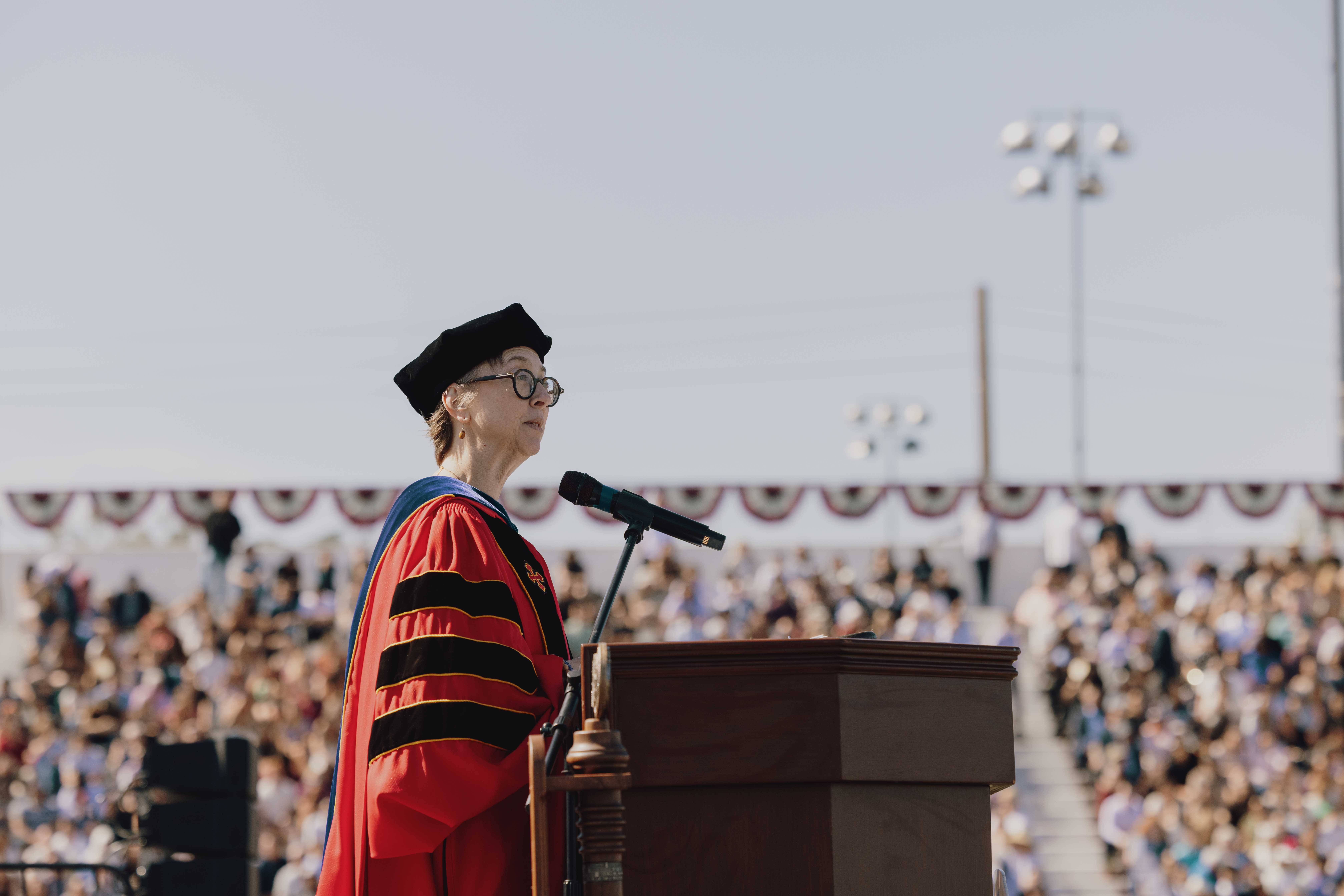 a person in a graduation gown standing at a podium with a microphone