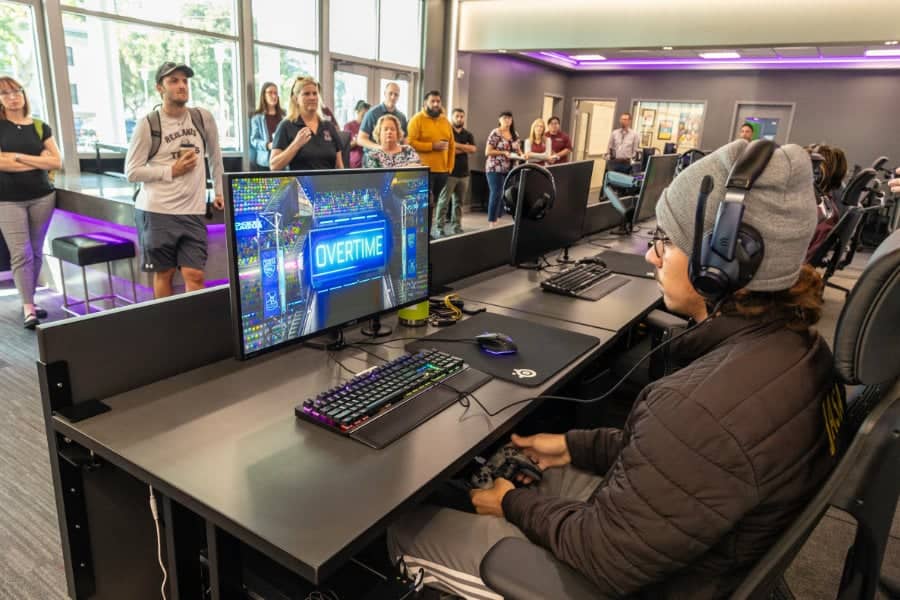 a person sitting at a desk with a computer and a group of people