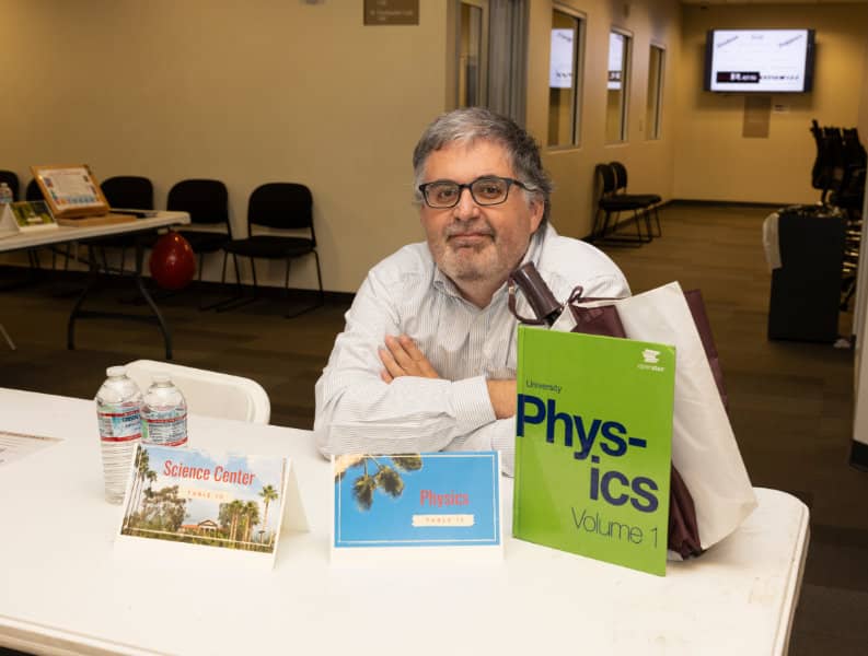 a person sitting at a table with books and a bag