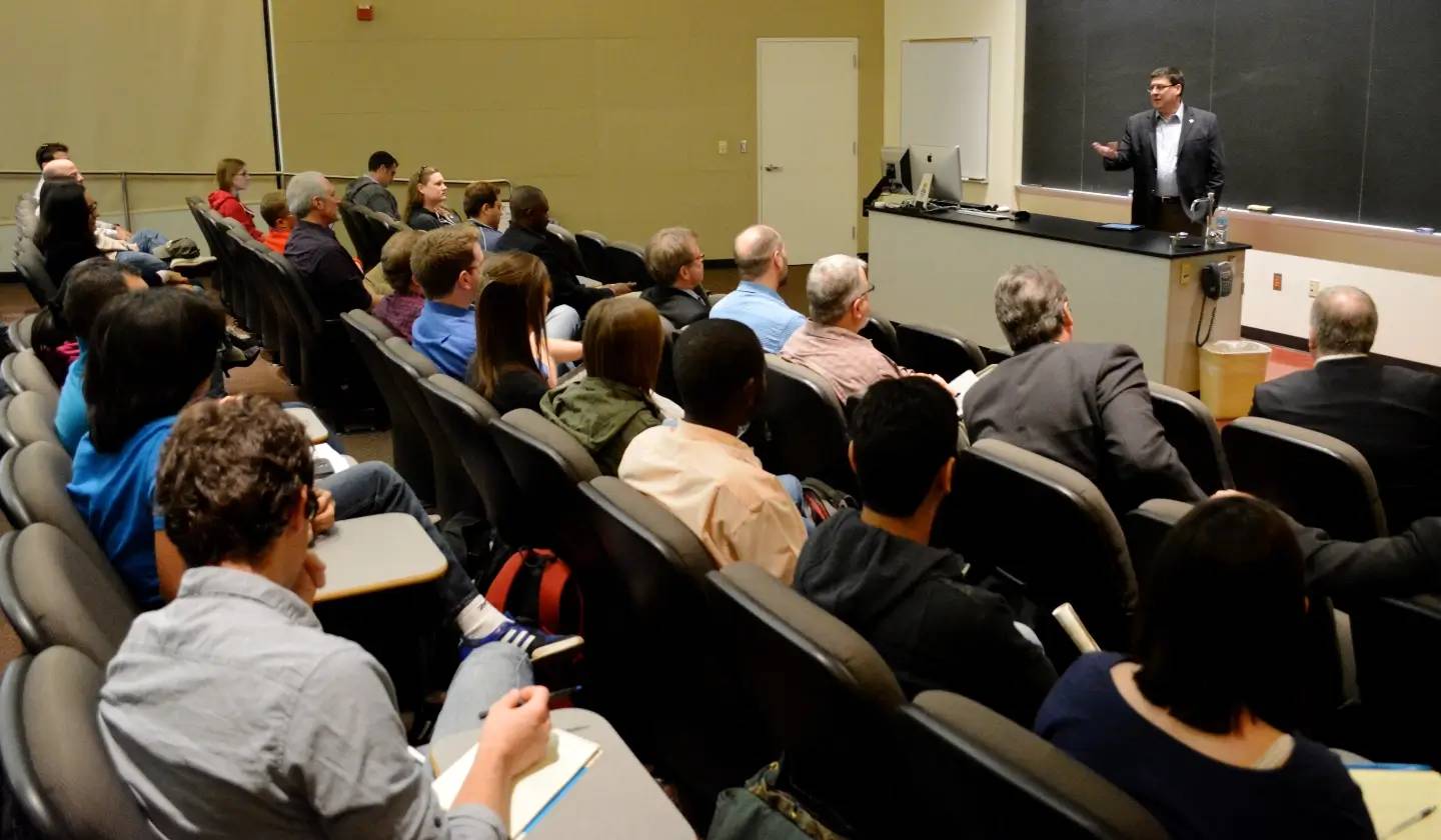 a person standing in front of a group of people in a lecture hall