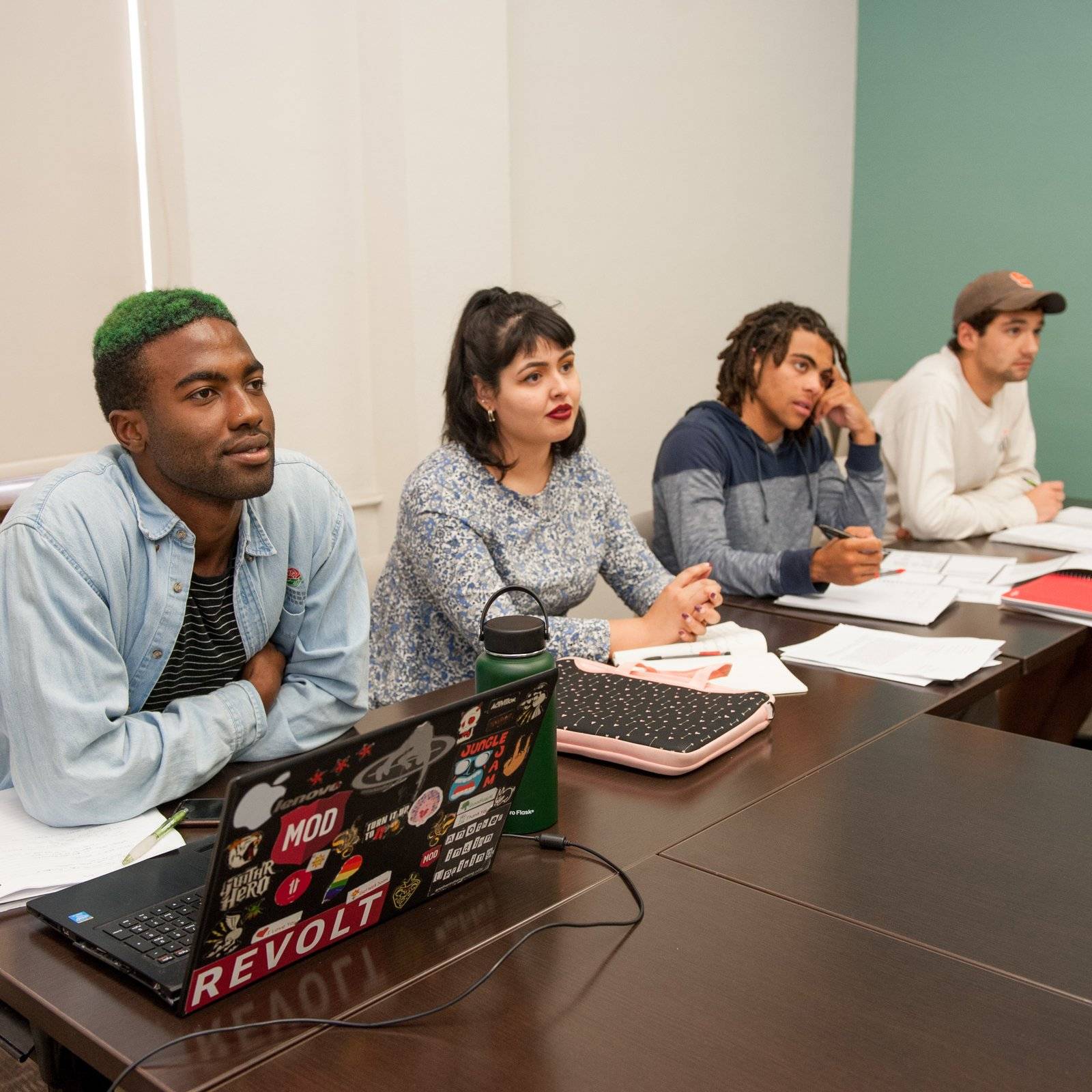 a group of people sitting at a table with laptops