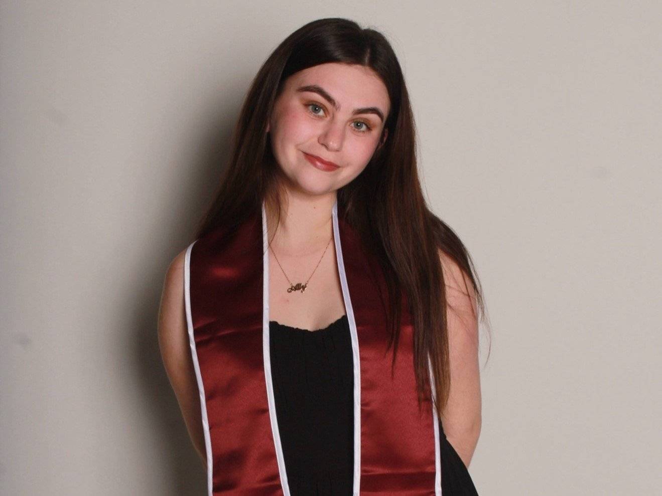 a person wearing a red and black dress and a sash