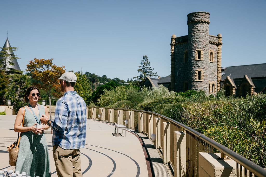 a person and person standing on a walkway with a castle in the background