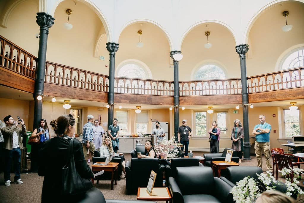 a group of people in a room with arches and columns