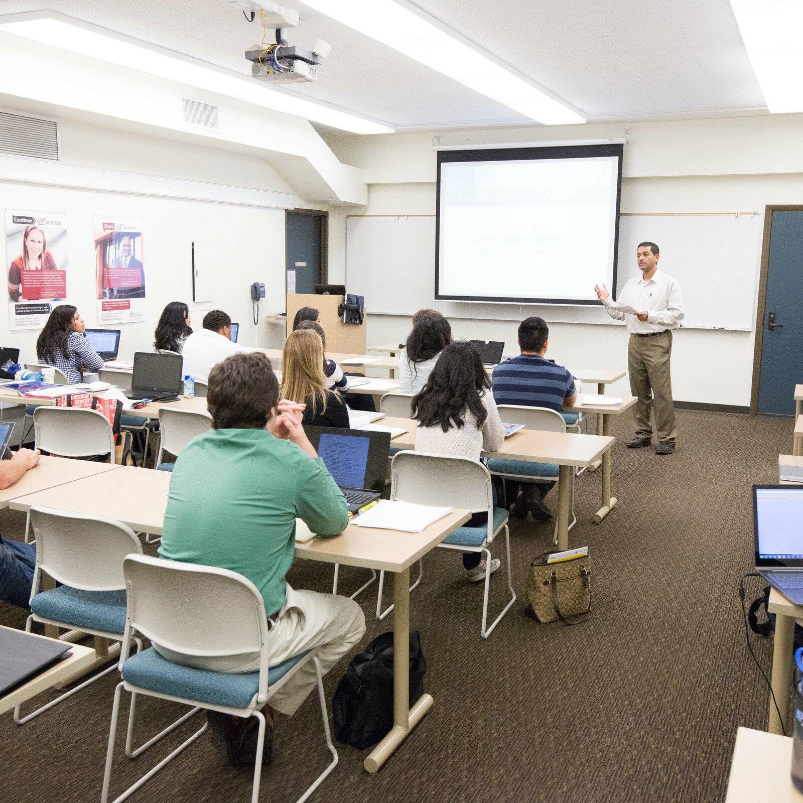 a person standing in front of a classroom with a group of people