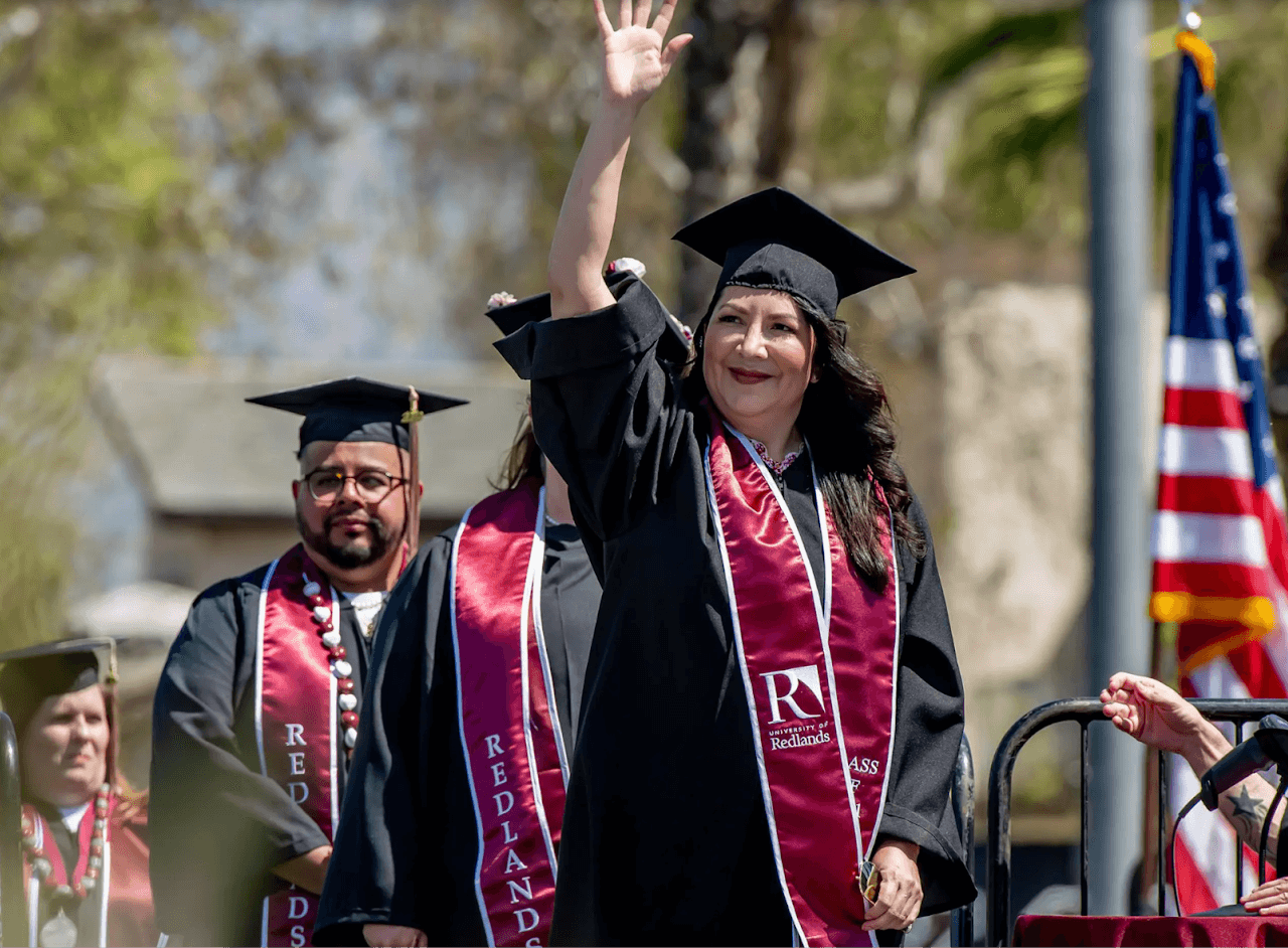 a person in graduation gown and cap waving