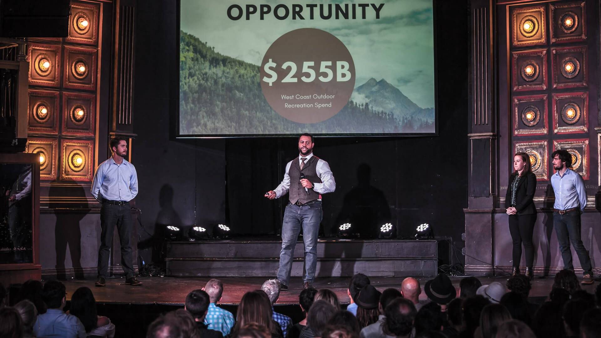 a person on a stage with a large screen and a large crowd