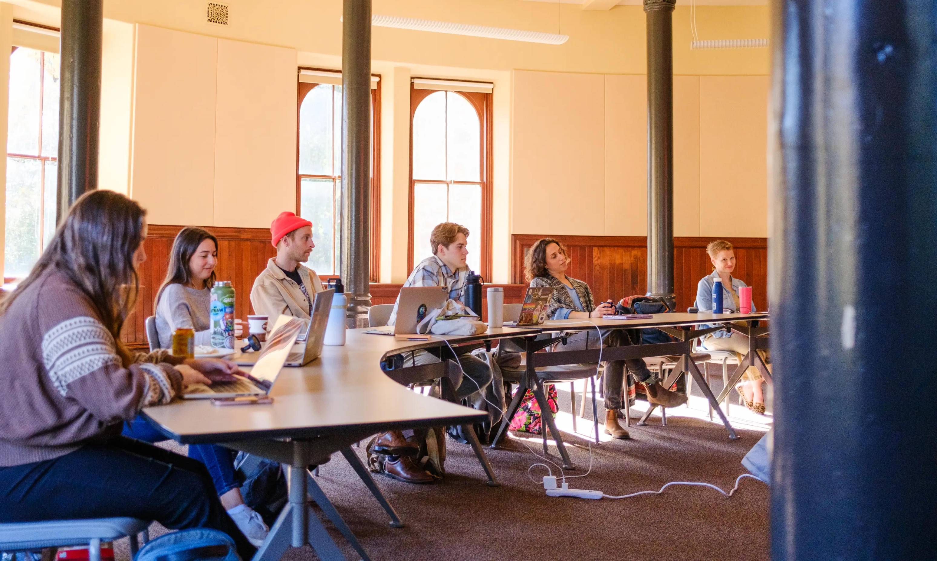 a group of people sitting at tables with laptops