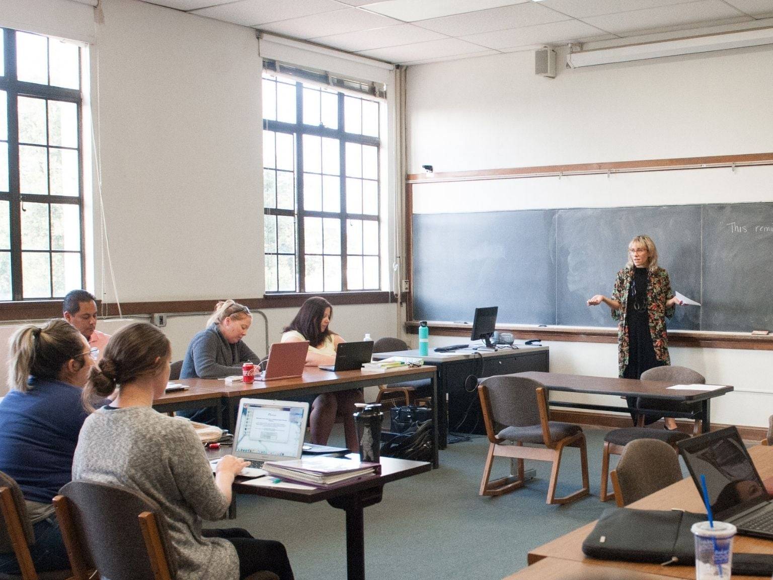 a person standing in front of a chalkboard in a classroom