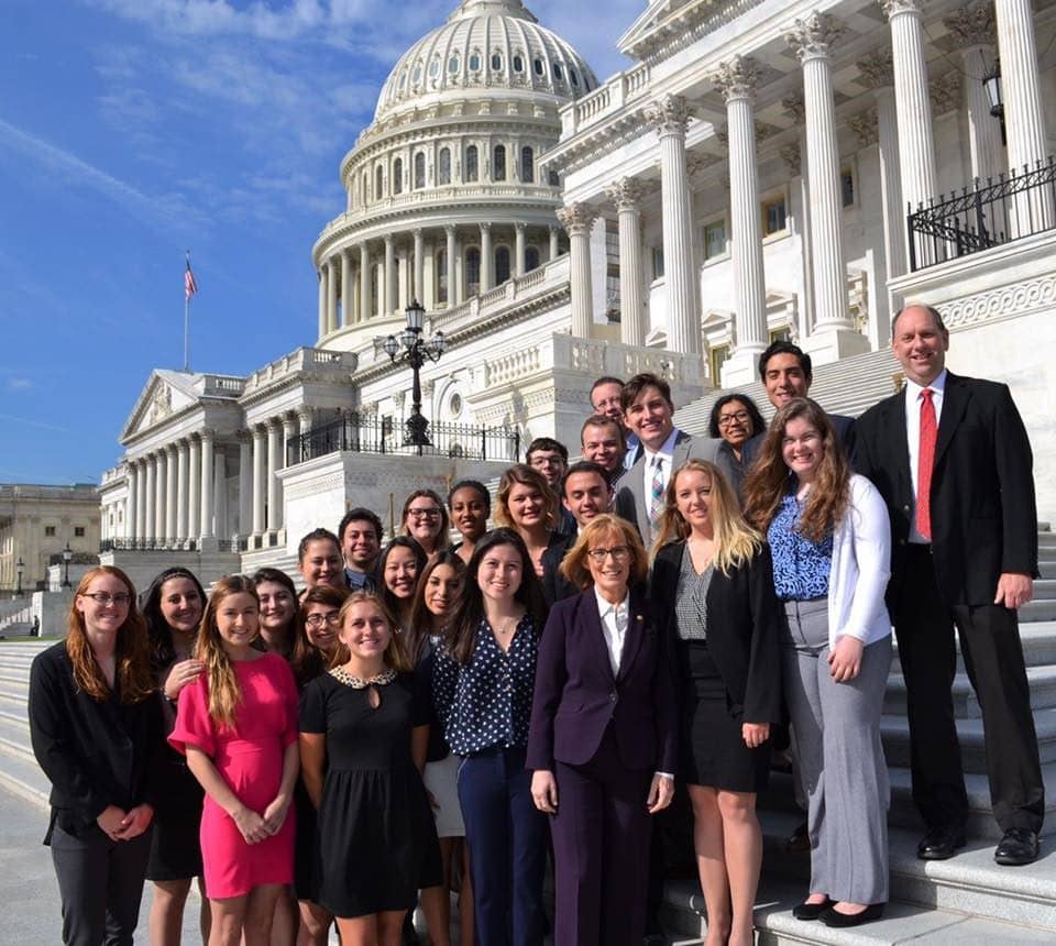 a group of people posing for a photo in front of a white building