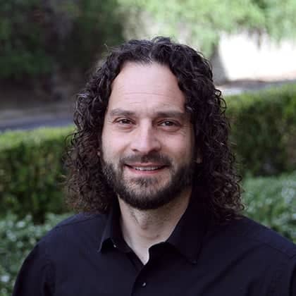 a person with long curly hair and beard smiling