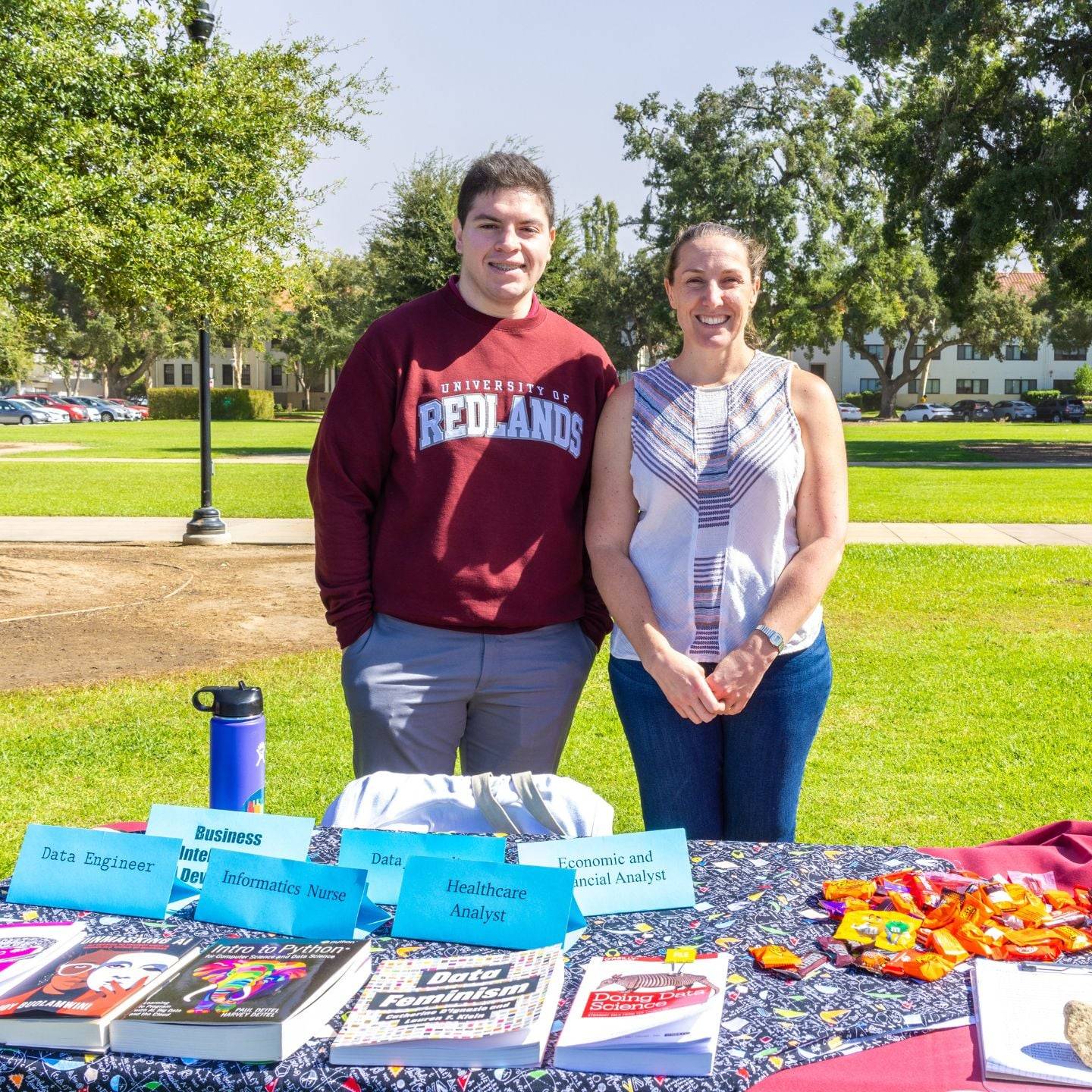 a person and person standing next to a table with books and papers