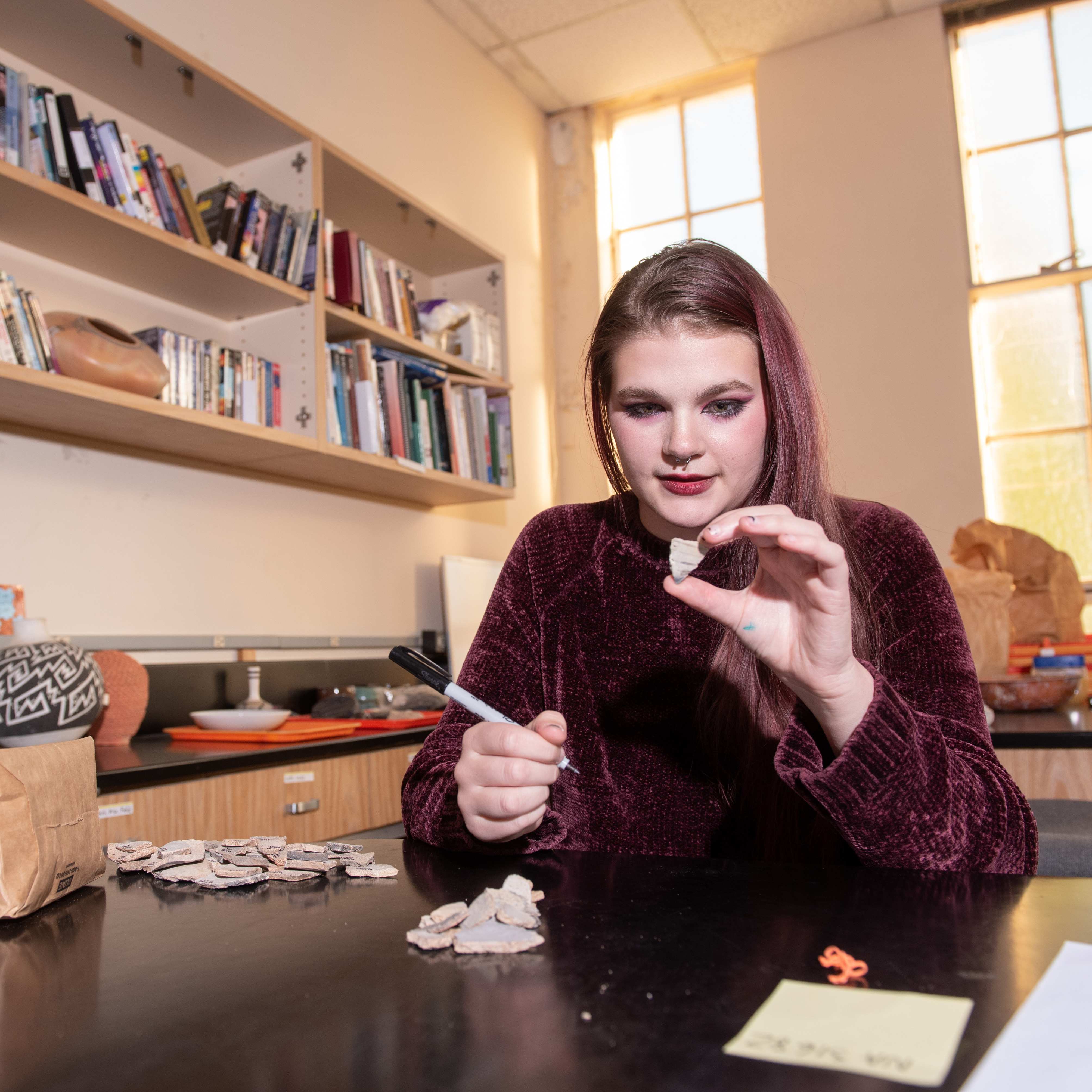 a child sitting at a table with a pen and a piece of clay