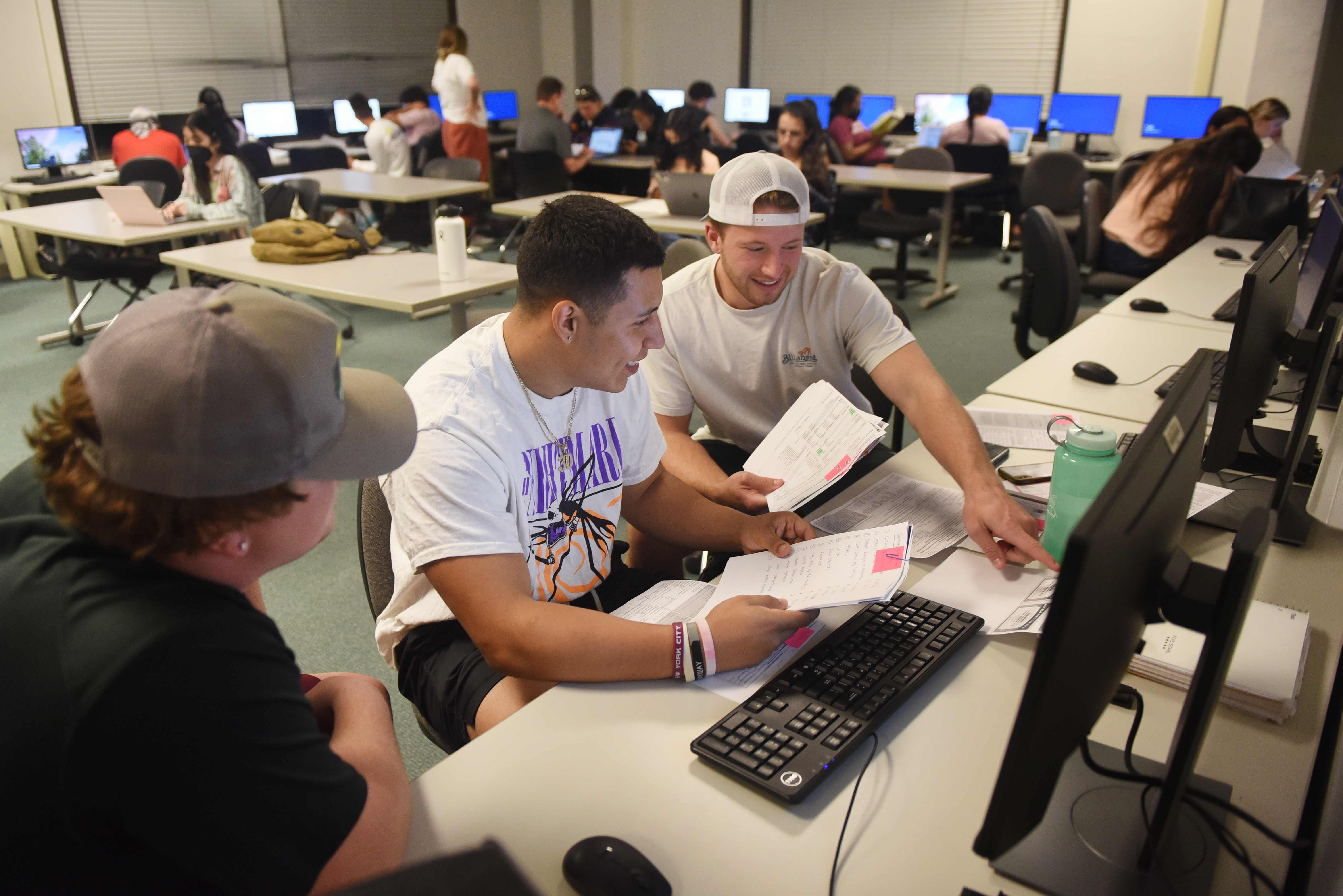 a group of people sitting at a desk with computers