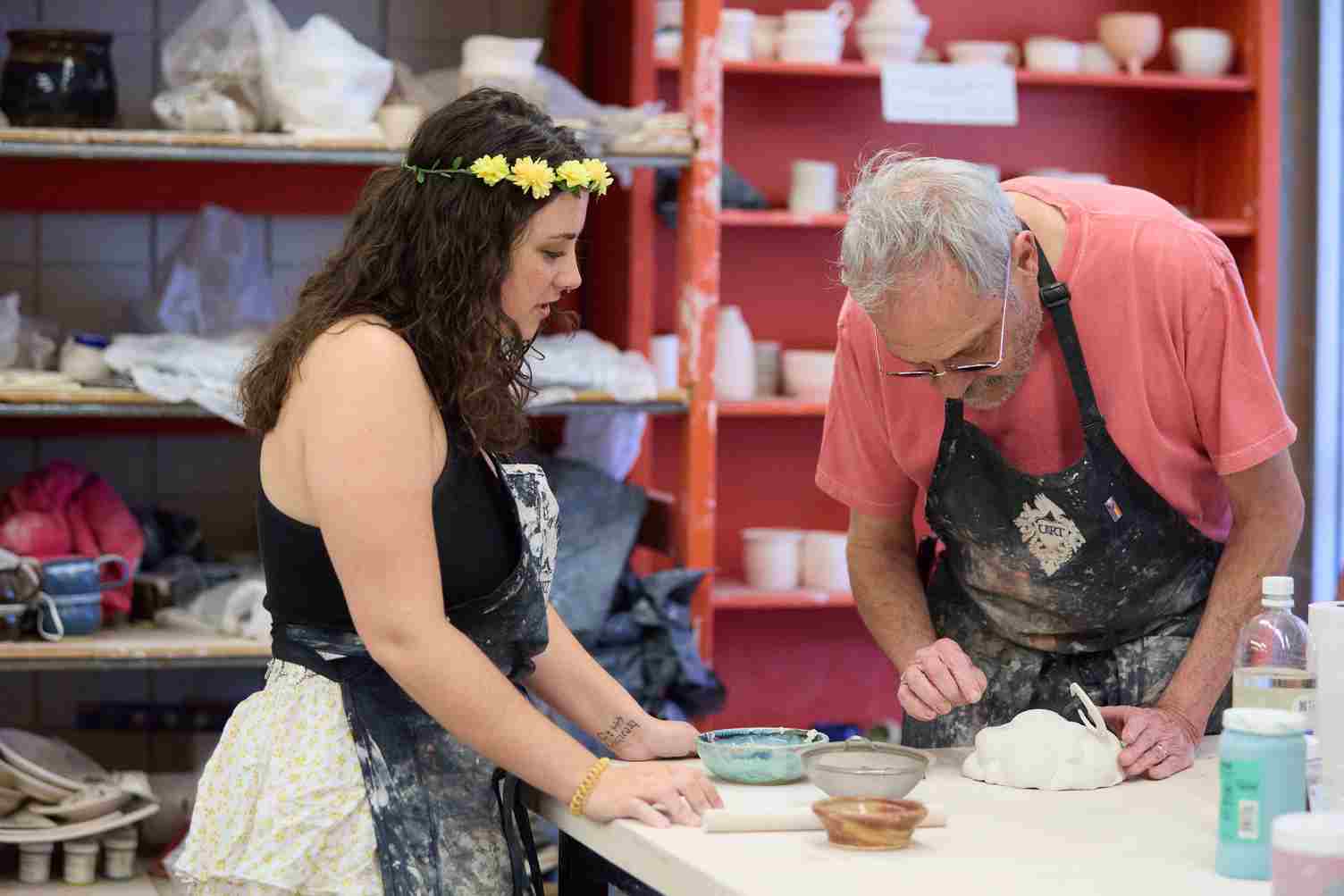 a person and person in aprons working on a pottery project