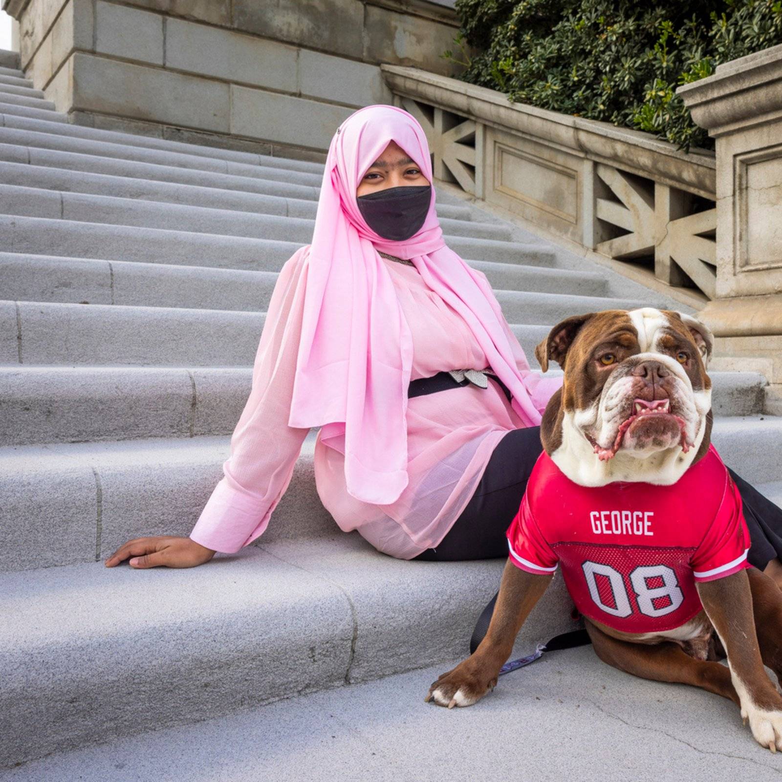 a person wearing a face mask sitting on stairs with a dog