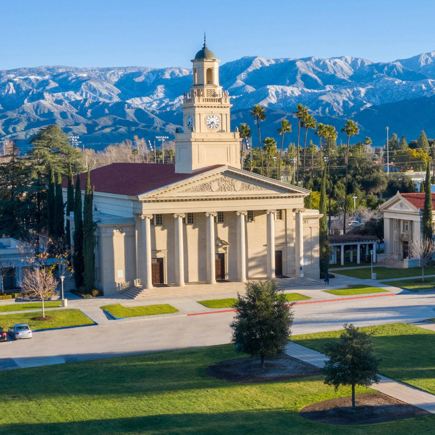 a building with a clock tower and trees and mountains in the background