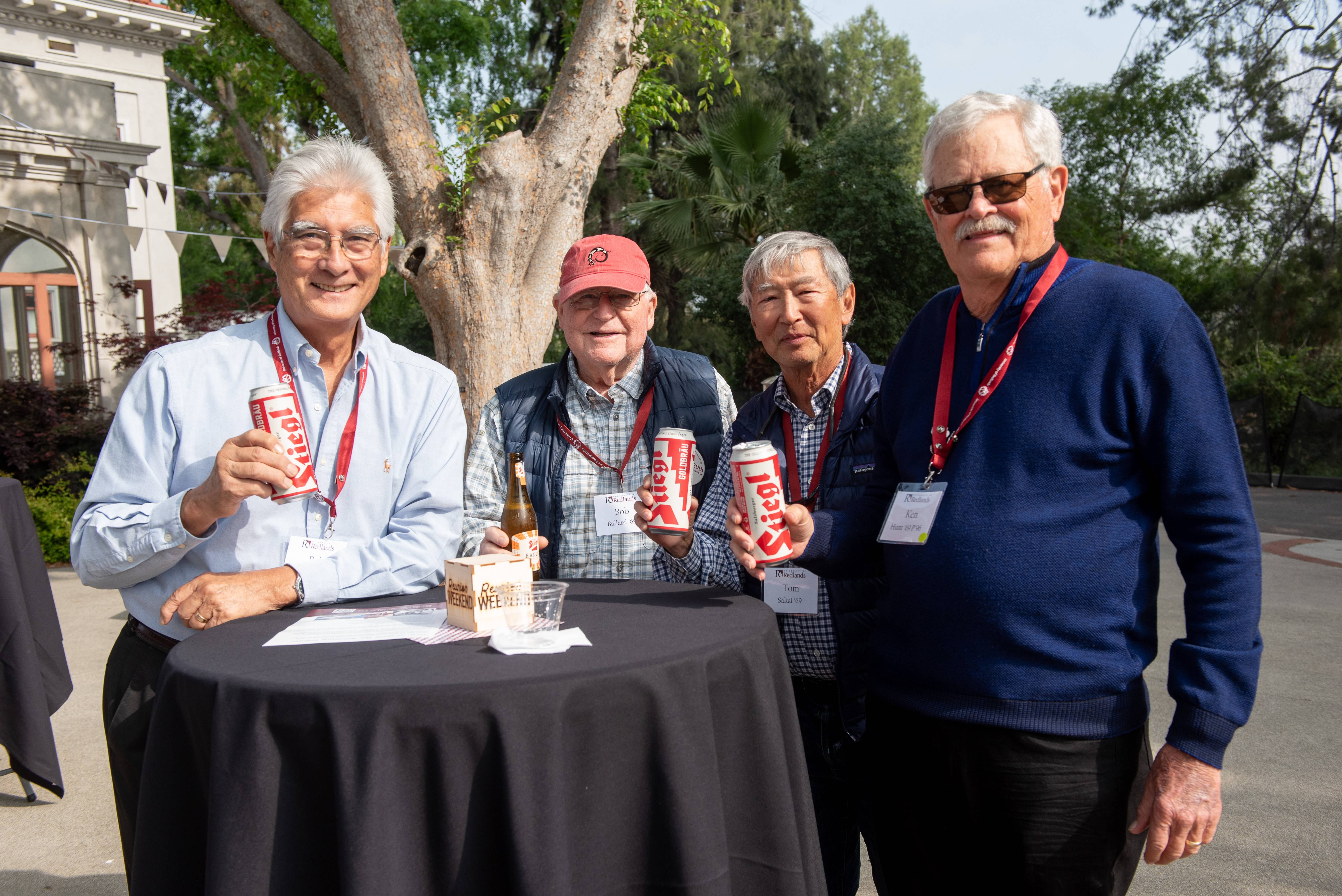 a group of men holding cans and standing at a table