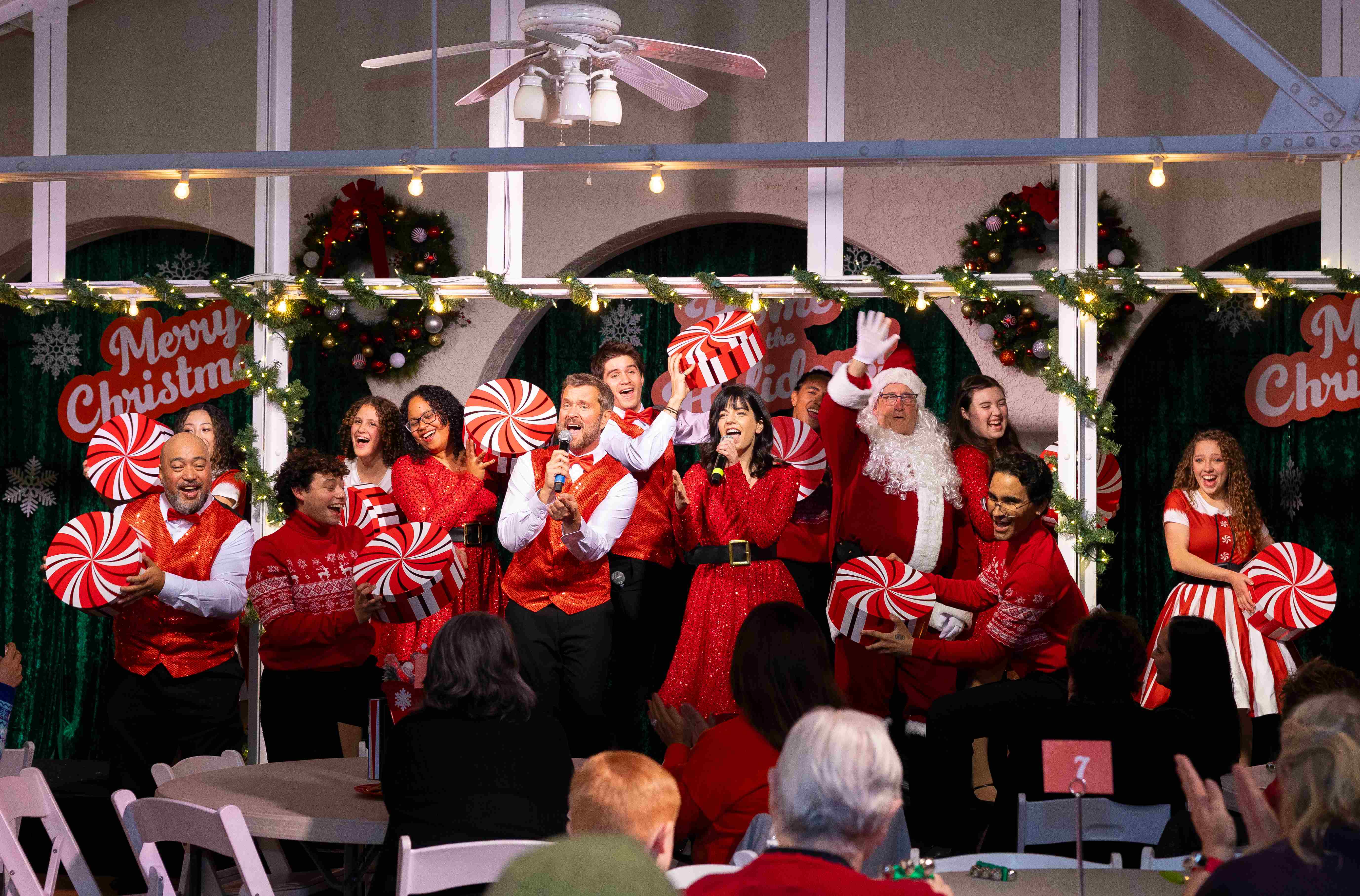 a group of people in red and white outfits singing and holding candy
