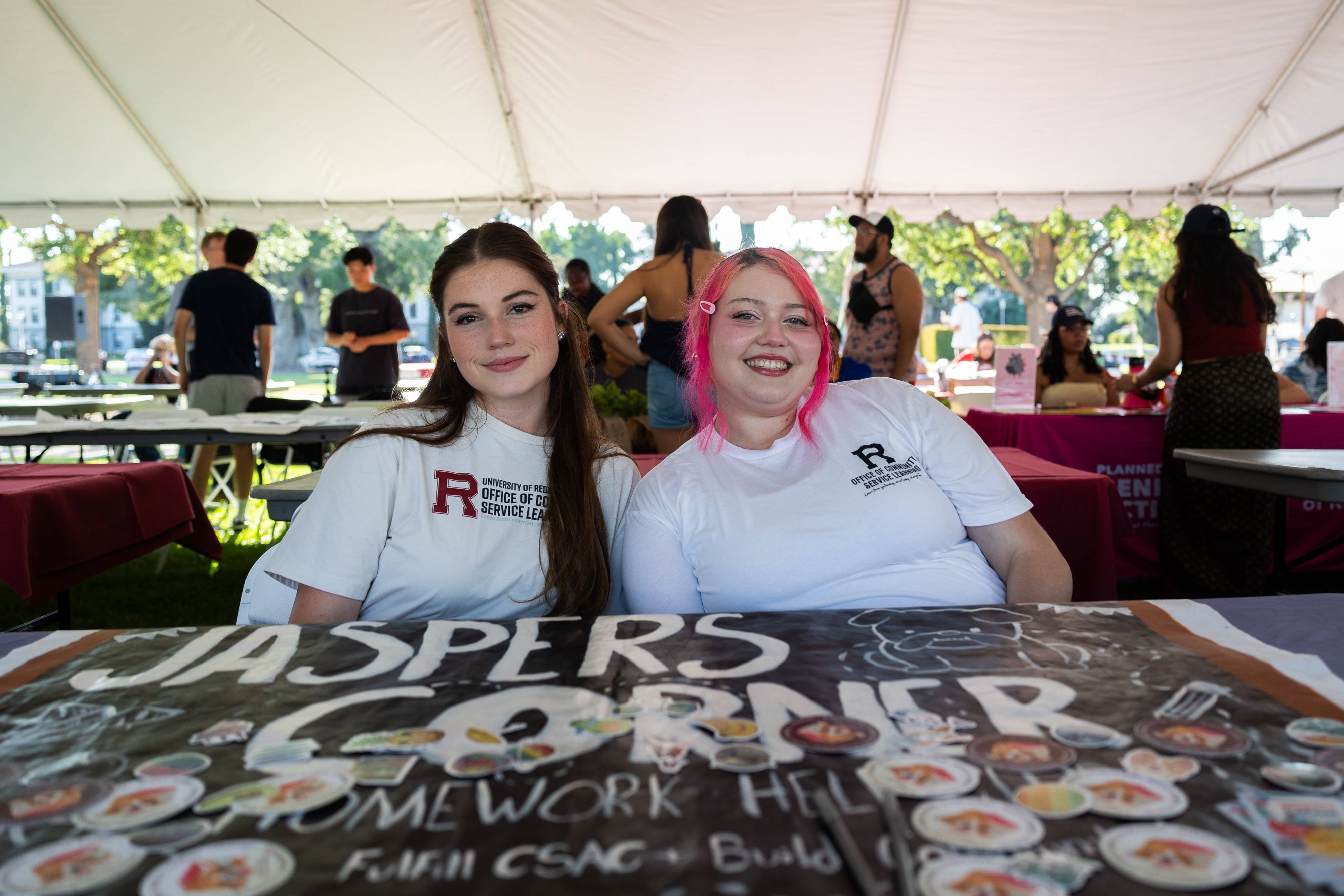two women sitting at a table under a tent