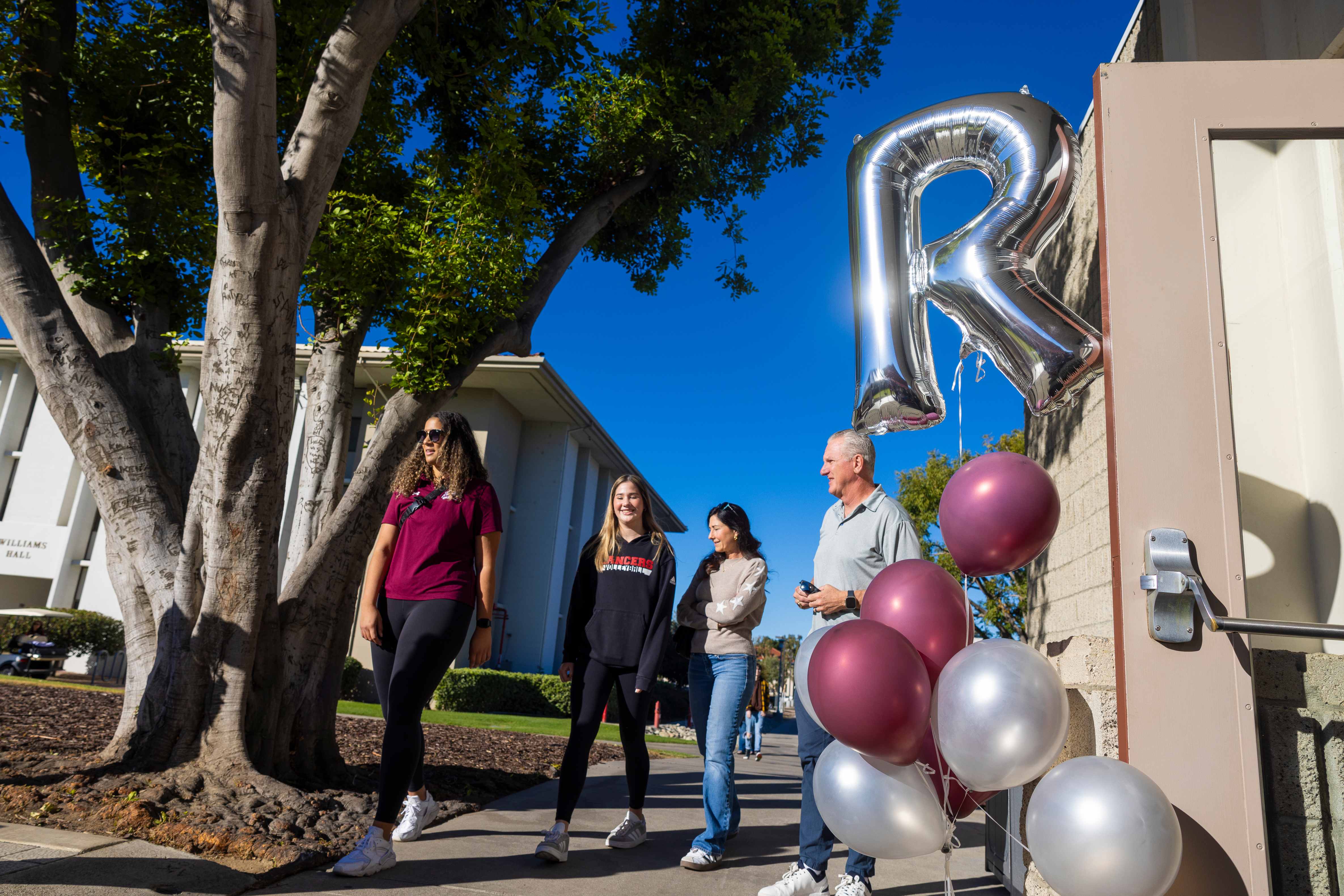 a group of people walking on a sidewalk with balloons