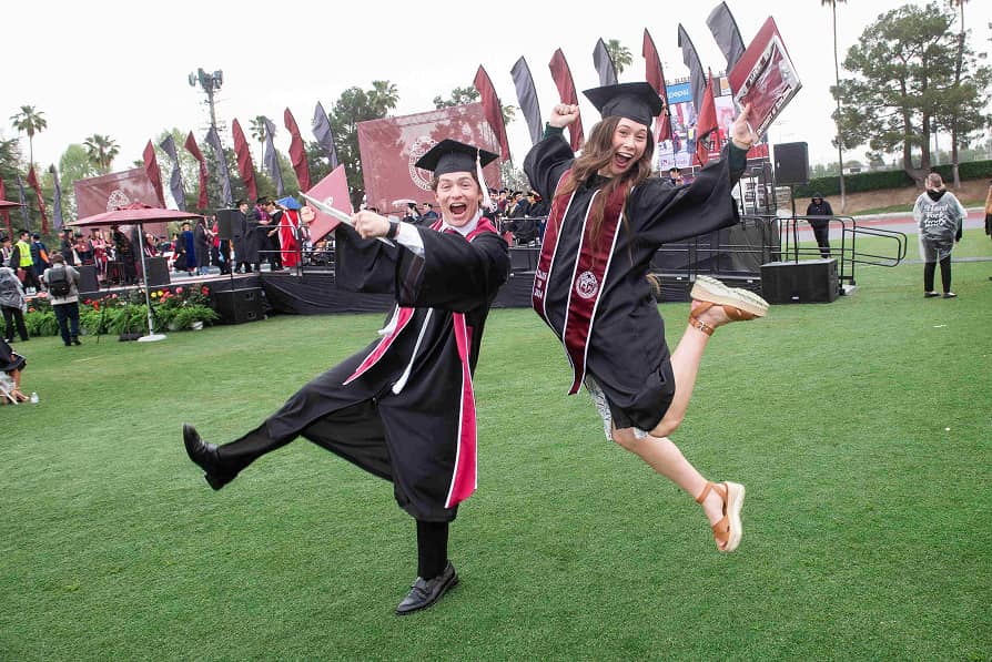 Two students jumping in the air celebrating.