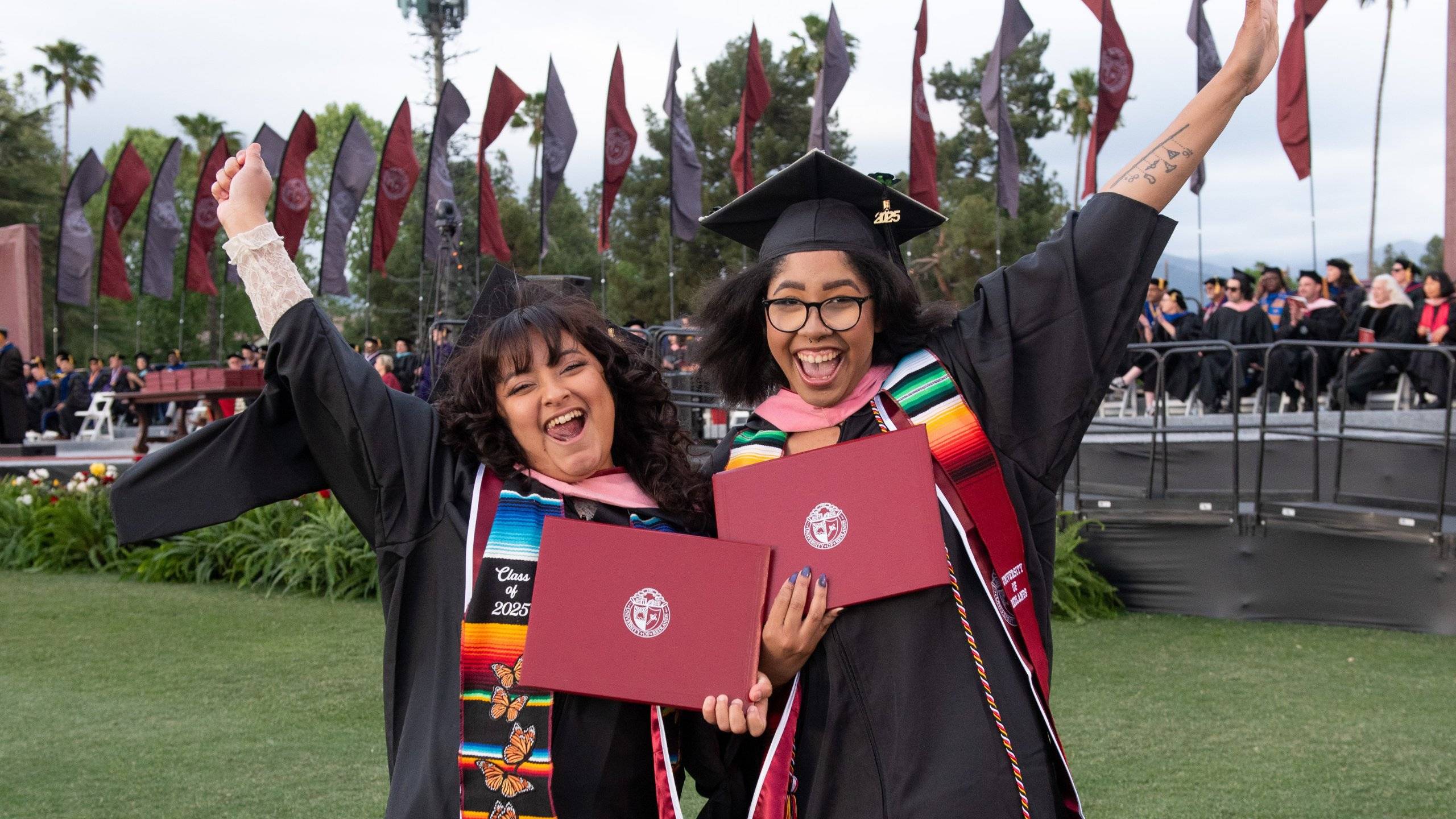 two women in graduation gowns and cap and gowns holding diplomas