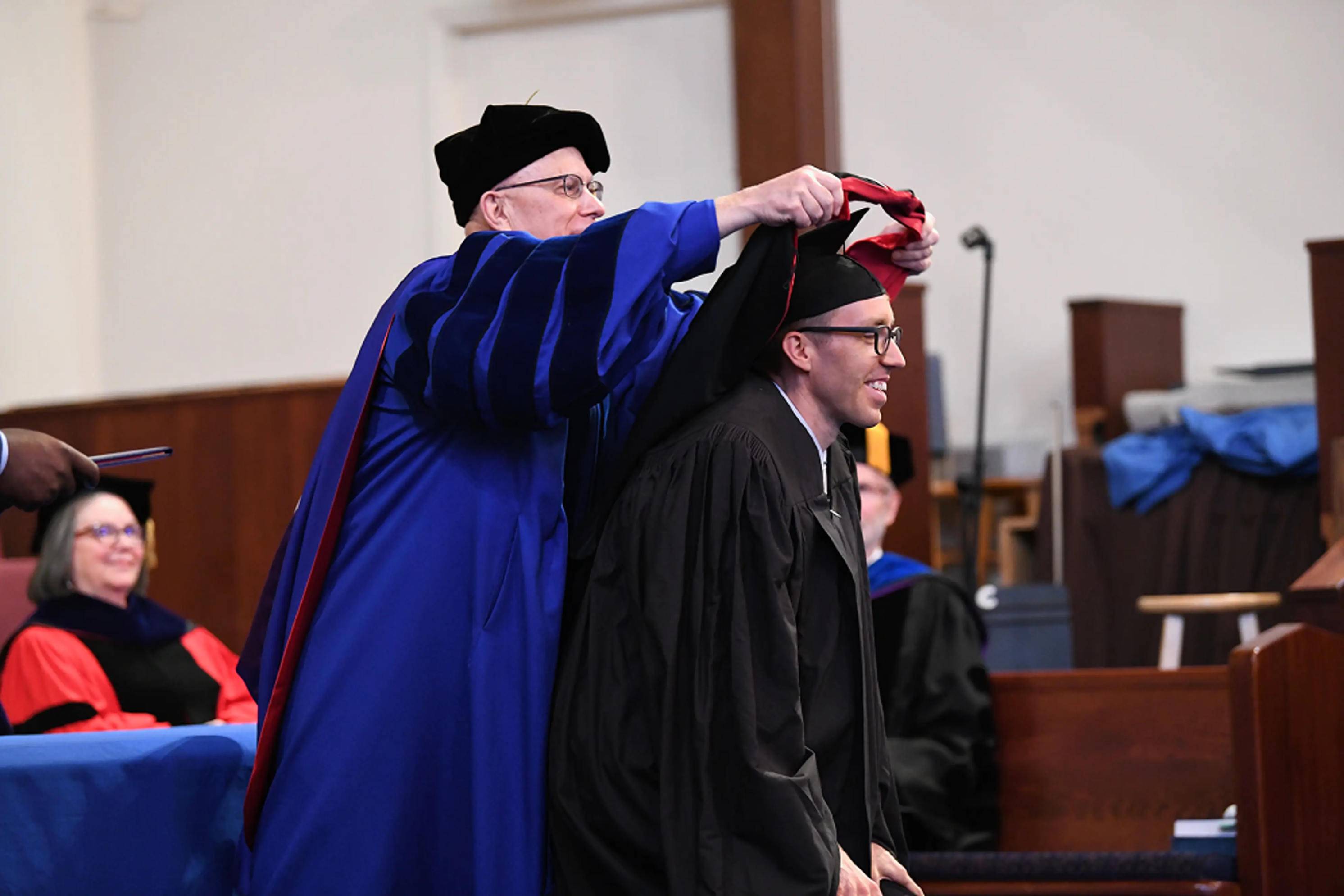 a person putting a red and black robe on a person's head